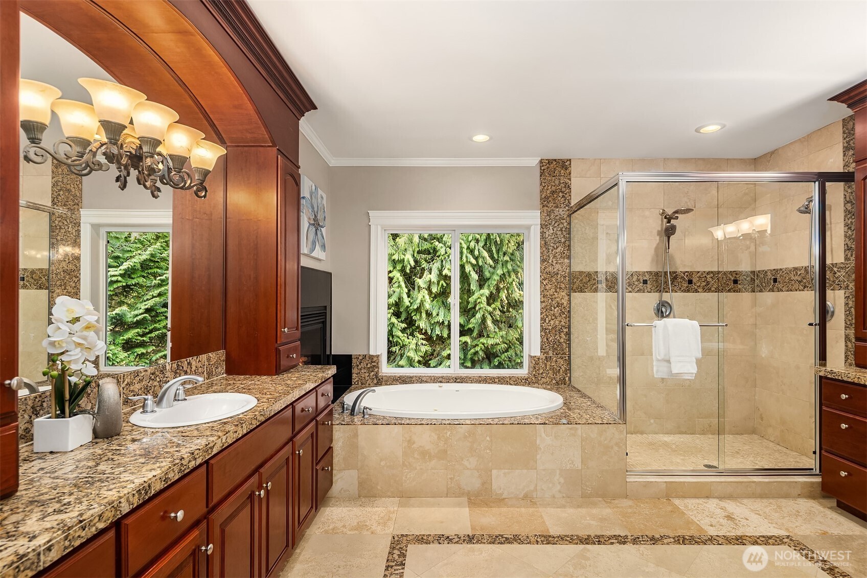 Classically designed bathroom with dual vanities and soaking tub in front of the fireplace.