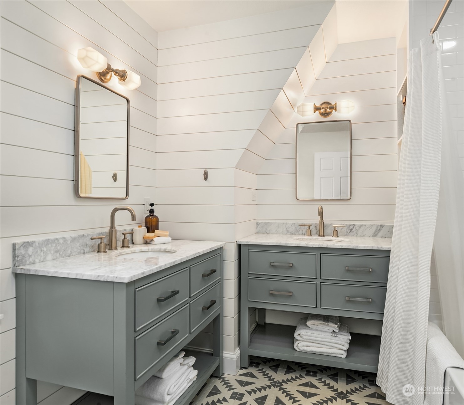 Shared hall bathroom with shiplap, two vanities, cement tile flooring and bathtub with gold fixtures.