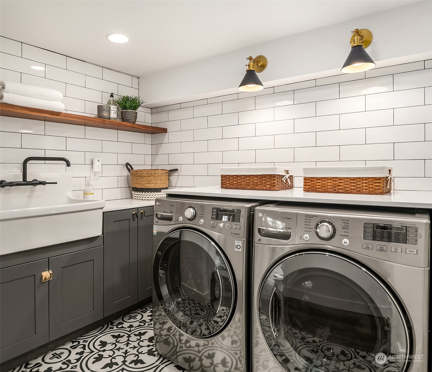 Lower level laundry with reproduction farmhouse sink, shaker style cabinetry, quartz countertops, subway tile surround, cement tile flooring and custom lighting