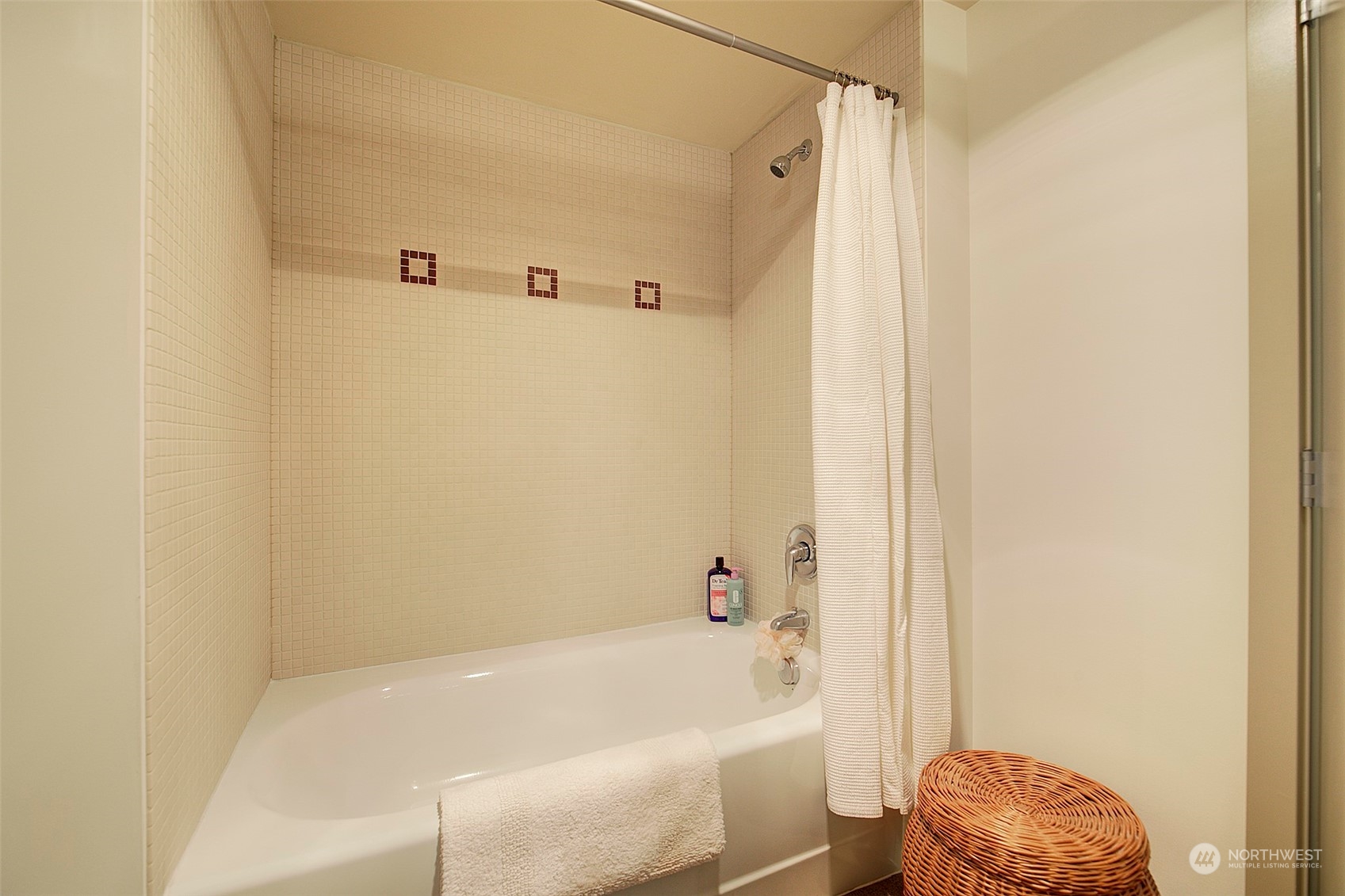 The bathtub/shower is lined in beautiful ceramic tile with custom touches.