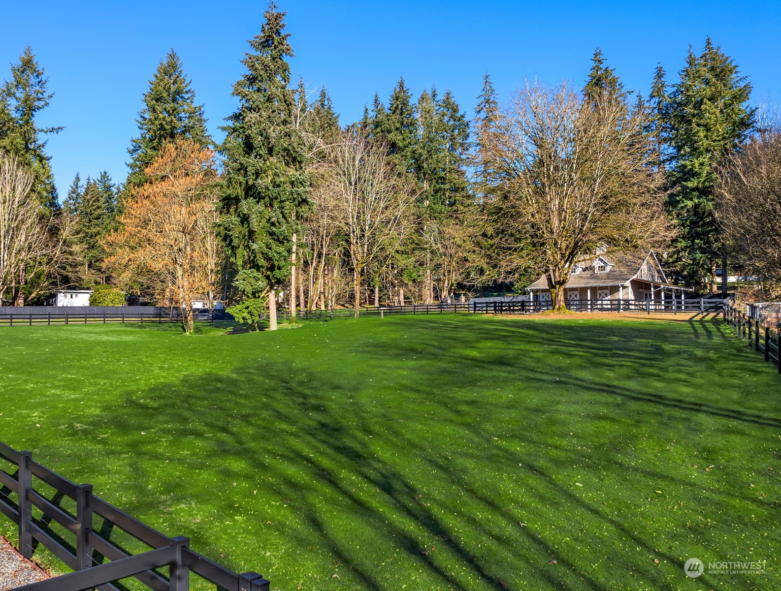 Lush pastures surrounded by 3-rail black vinyl fencing.