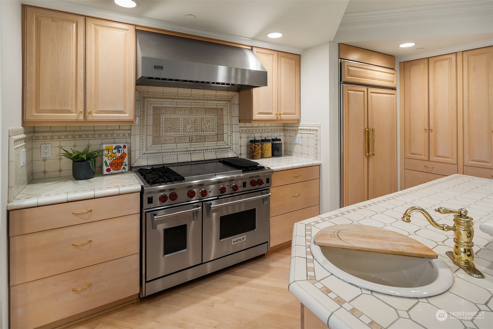 This timeless grand Wolf Range and double ovens, the custom tile backsplash and counters, and cabinetry enclosed Sub zero Fridge are so on-trend now.