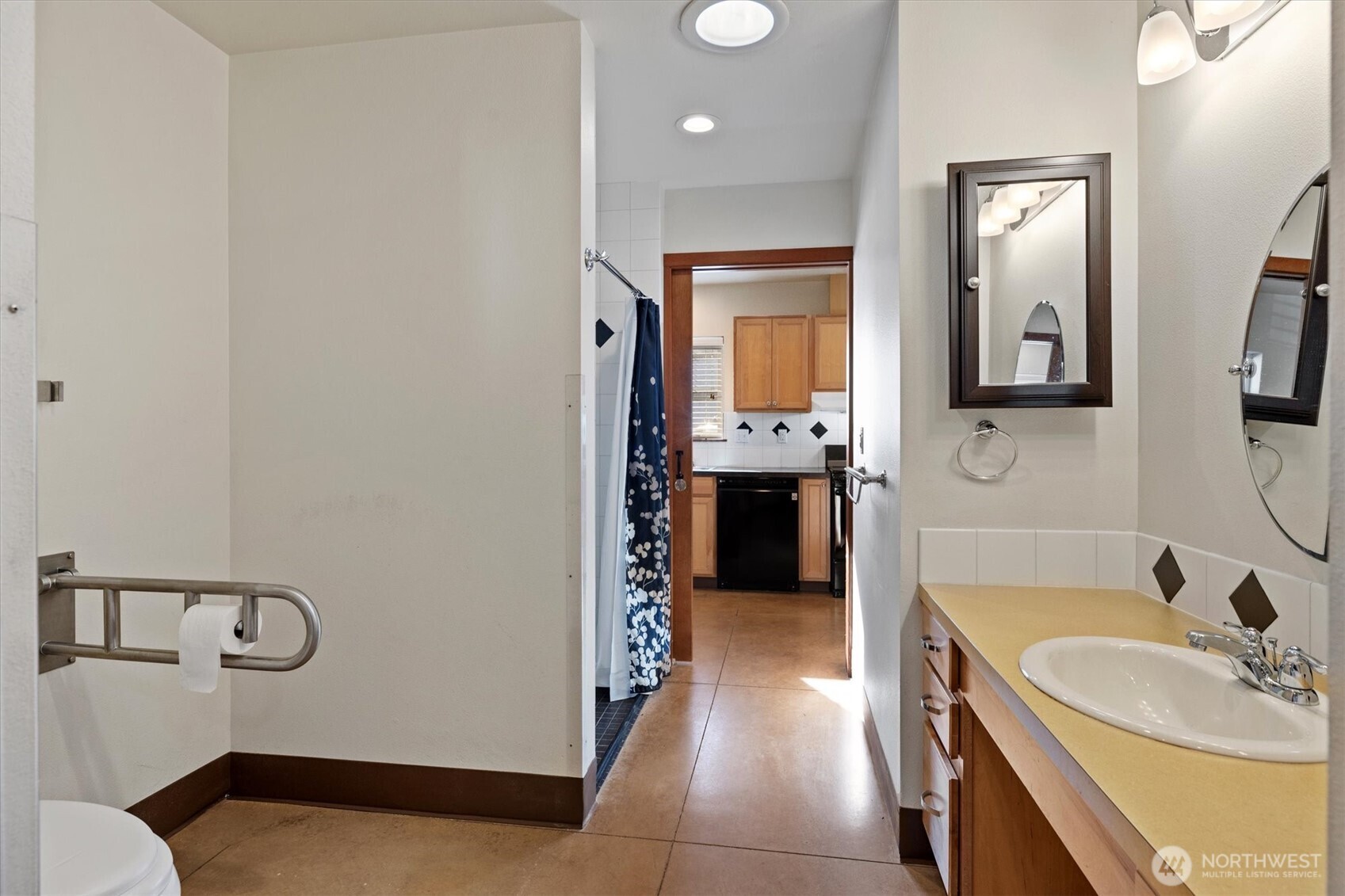 ADA bathroom with grab bars and a roll-in shower with seat