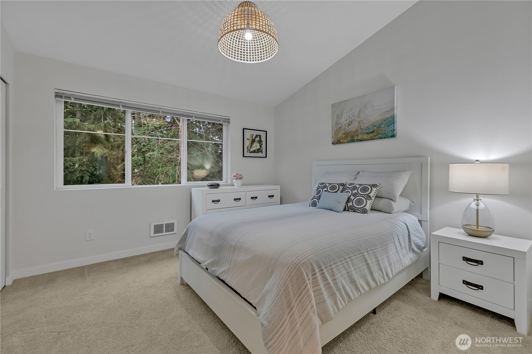 Primary bedroom boasts a vaulted ceiling and is accented with a large window to showcase the tranquil view.