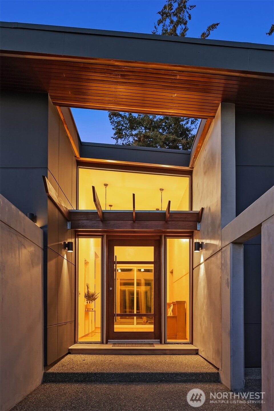 A striking concrete wall surrounds the entry, creating an air of mystery and privacy.