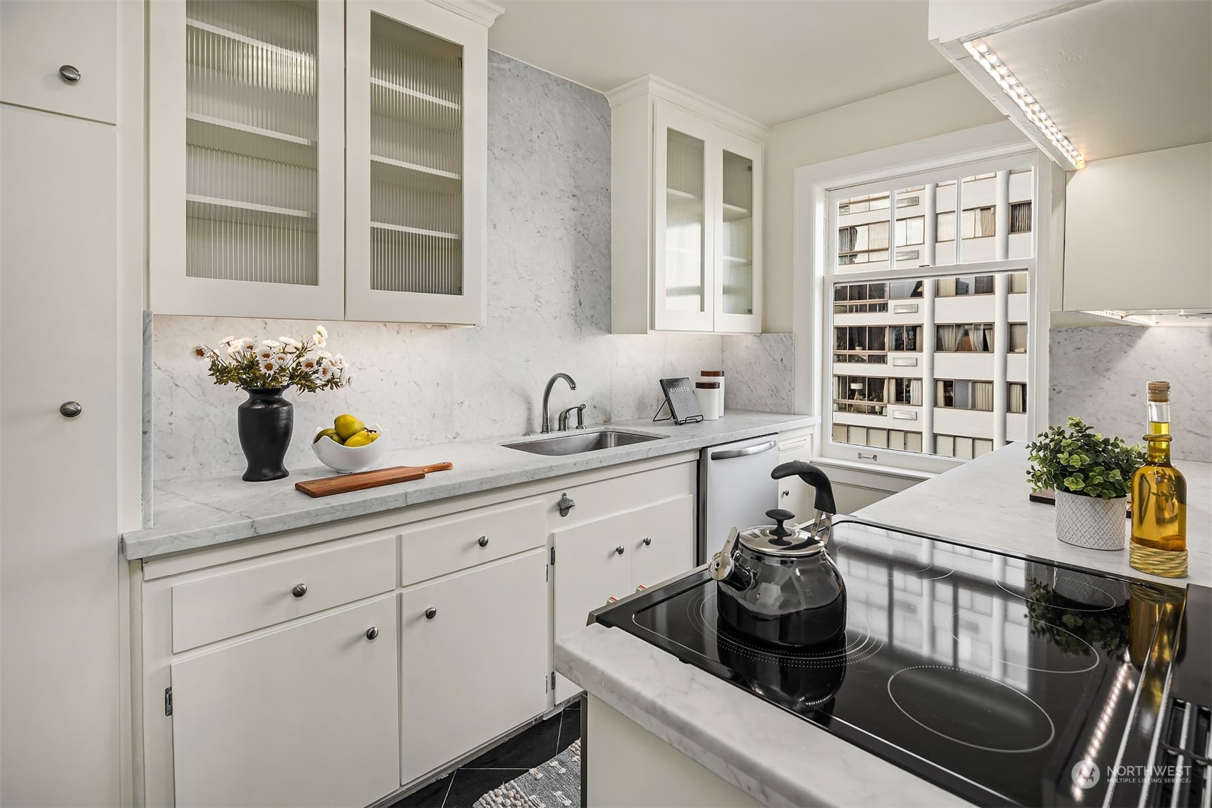 The galley kitchen has been updated with lovely black stone tile, Carrera marble countertops, new stove and dishwasher. Out of view is an additional "back door" that leads to the common area hallway.