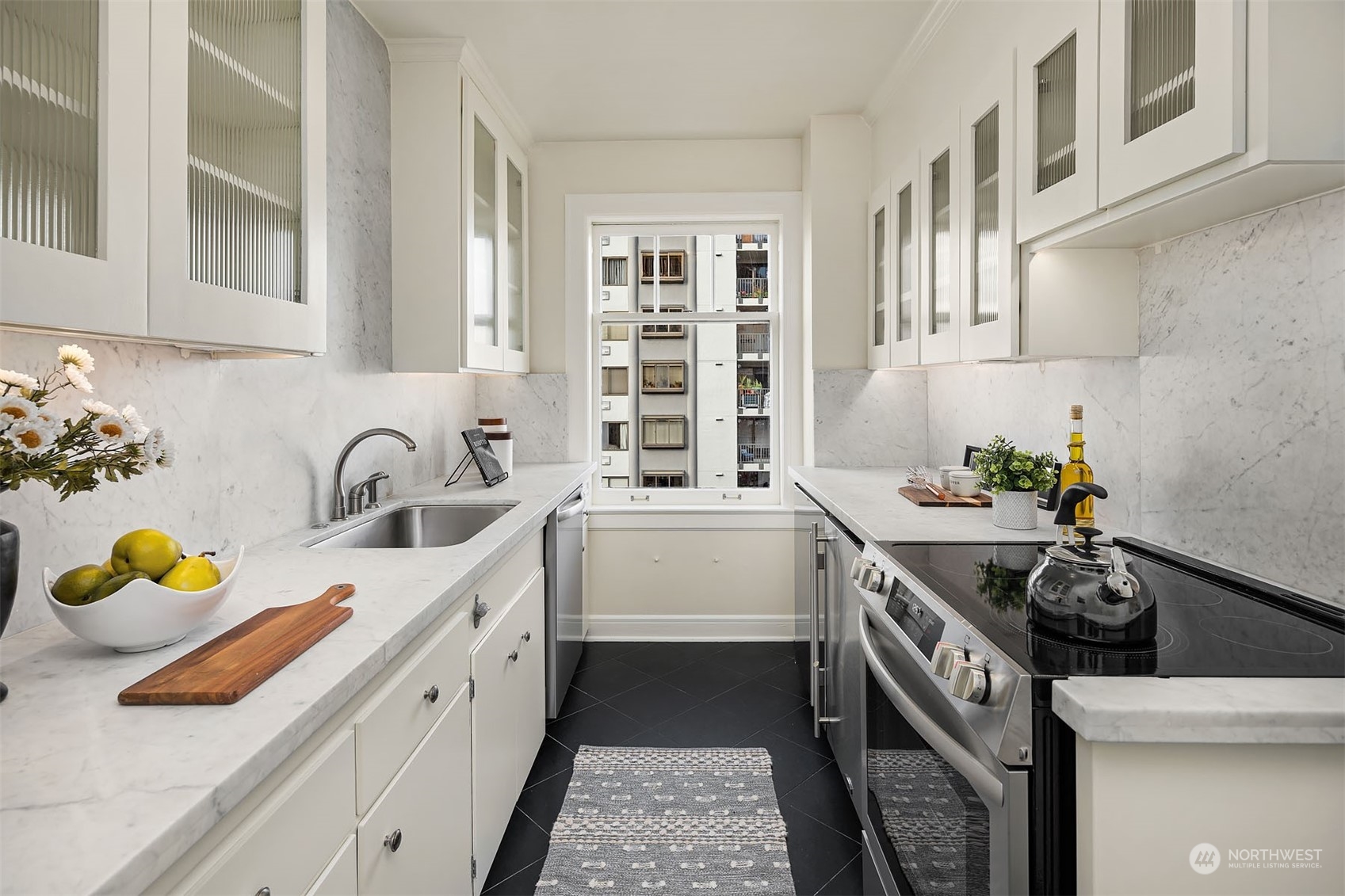 The galley kitchen has been updated with lovely black stone tile, Carrera marble countertops, new stove and dishwasher. Out of view is an additional "back door" that leads to the common area hallway.