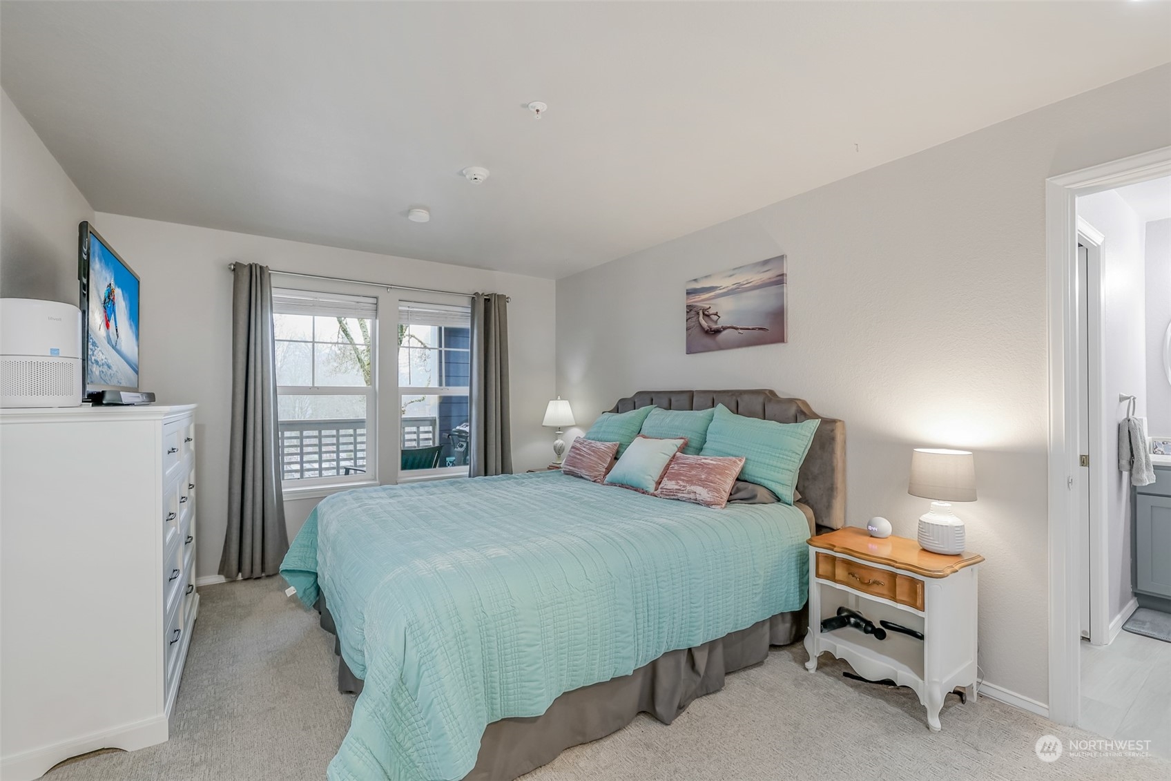 The spacious master suite offers a serene retreat, featuring large windows and a private balcony to enjoy fresh air and scenic views. Neutral tones and plush carpeting create a cozy yet sophisticated atmosphere, perfect for unwinding at the end of the day.