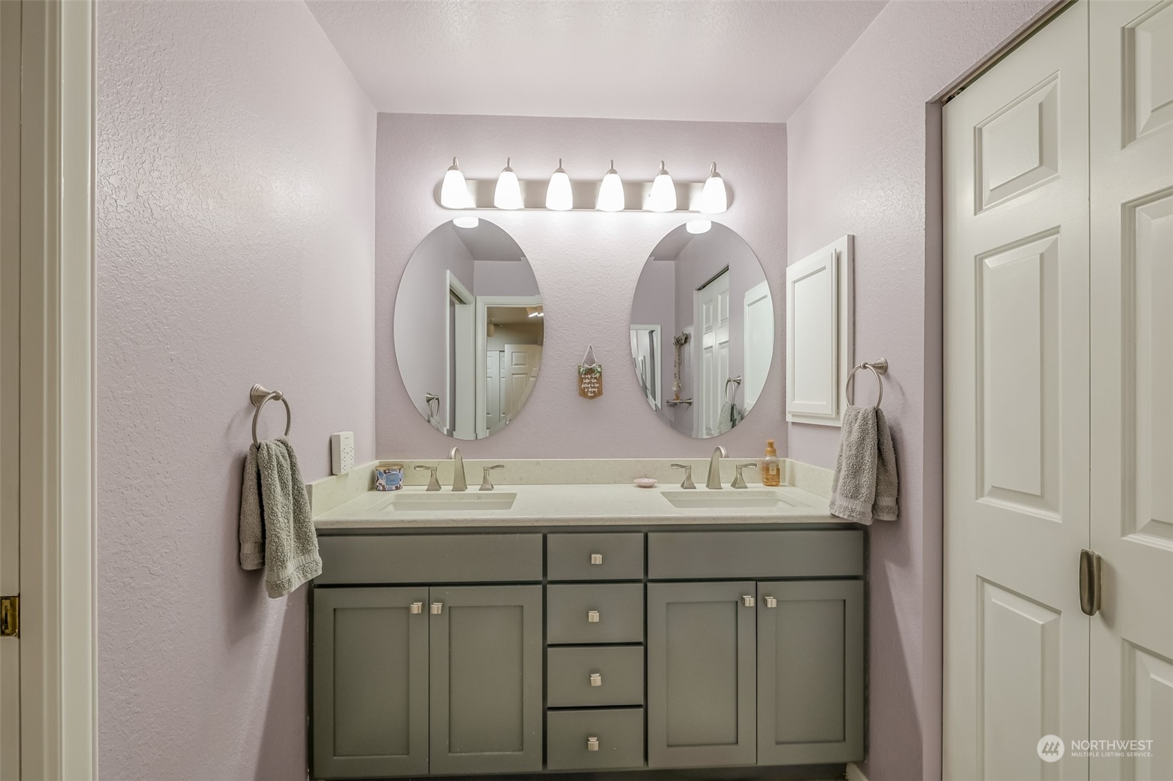 The remodeled primary bathroom boasts a sleek double vanity with modern fixtures and ample storage. Elegant lighting and soft, neutral tones enhance the spa-like feel, creating a relaxing and functional space.