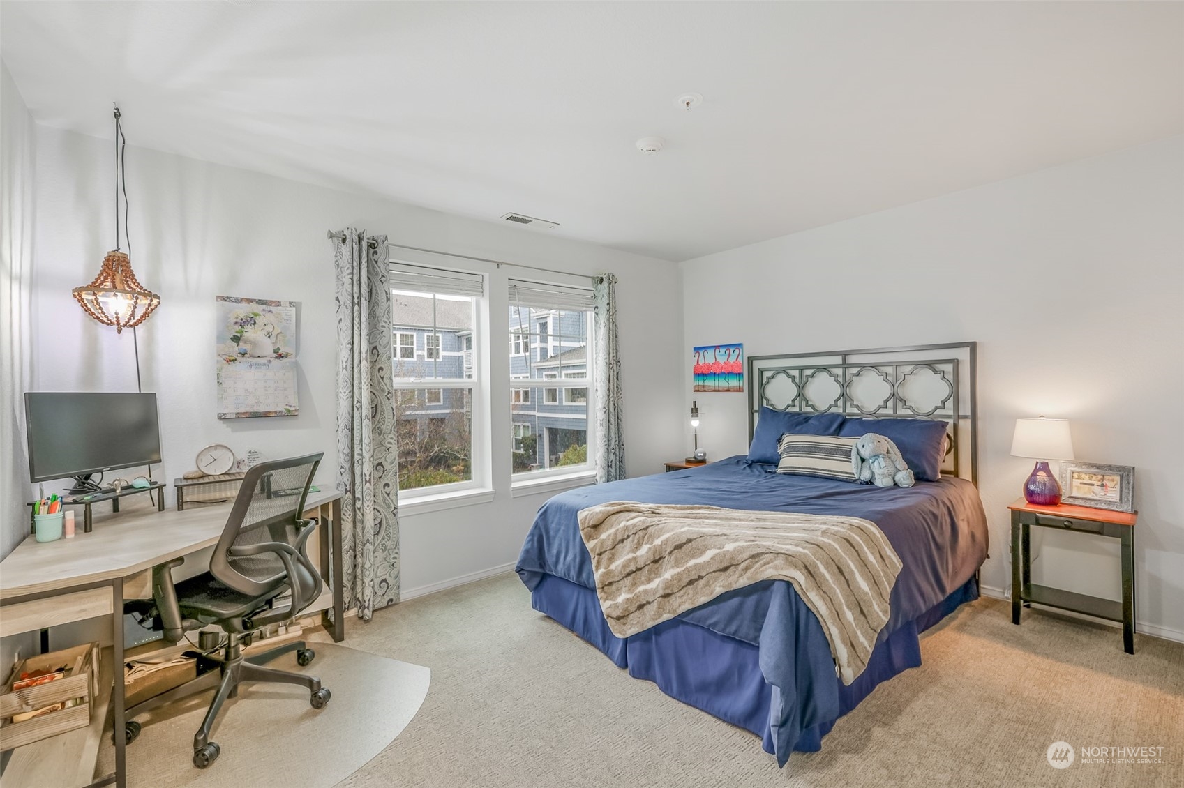 This generously sized guest bedroom offers flexibility for guests or a home office. Large windows fill the space with natural light, and the neutral palette provides a calm and welcoming environment