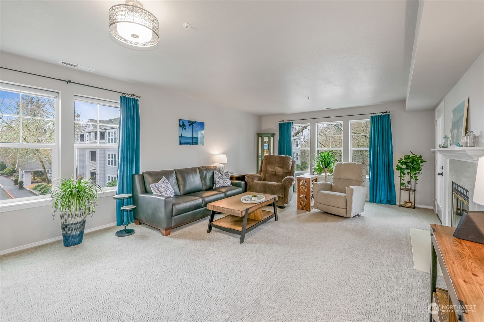 Flooded with natural light from oversized windows, this spacious living room provides a bright and airy atmosphere. The open floor plan is perfect for relaxation and entertaining, with tree-lined views adding a touch of tranquility. Plush carpeting and a soft color palette make this space feel both cozy and elegant.