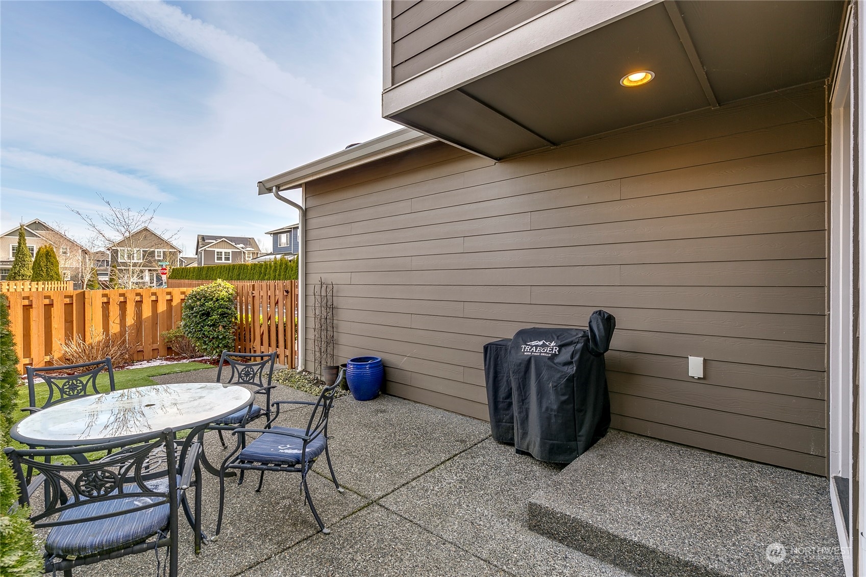 Side patio and fenced back yard with artificial grass.