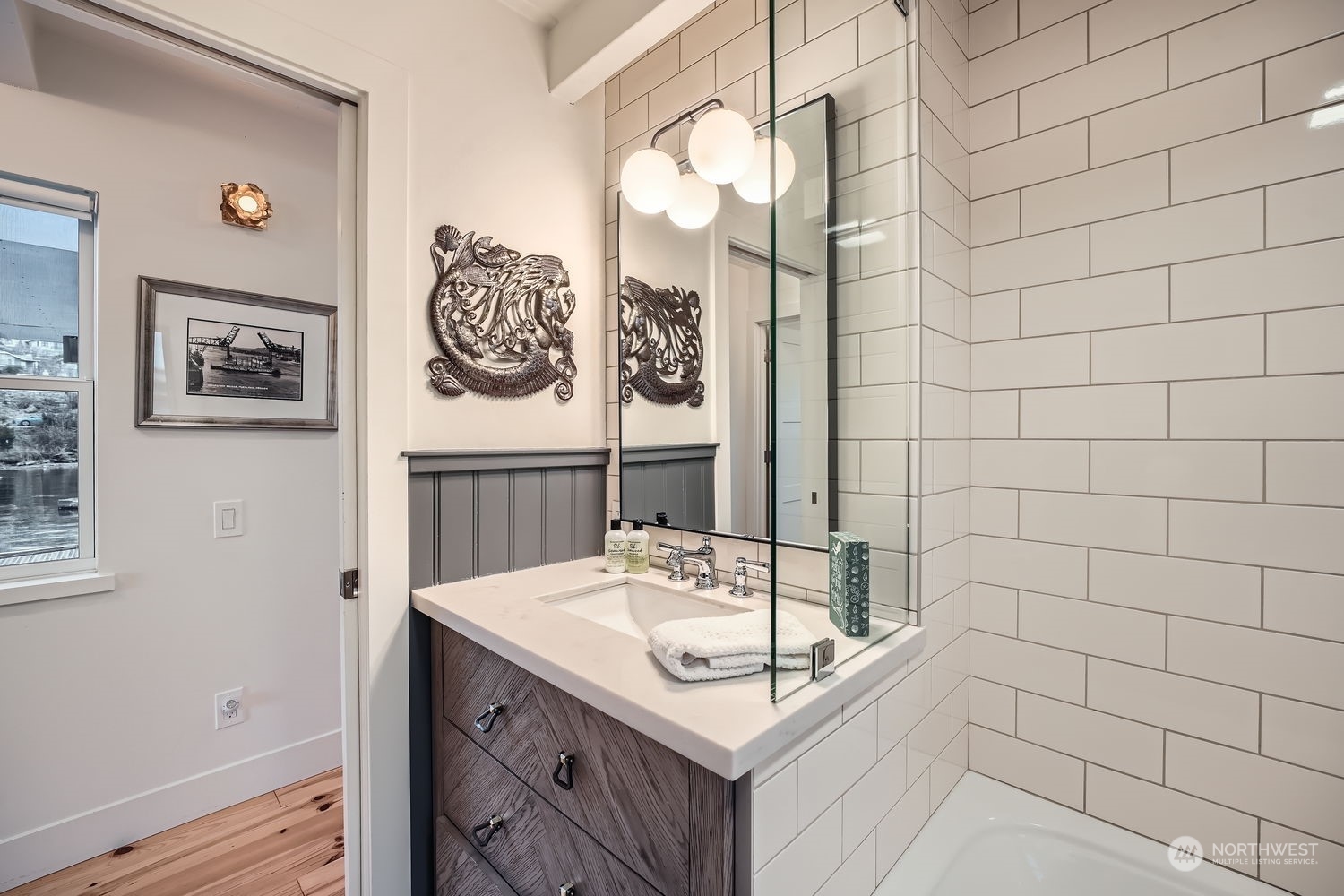 This is a full sized bathroom with tum/shower, boxcar tiled wall backsplash.