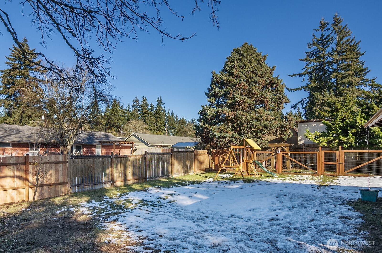 Massive, fully fenced yard with dog run, play structure, and gardening space.