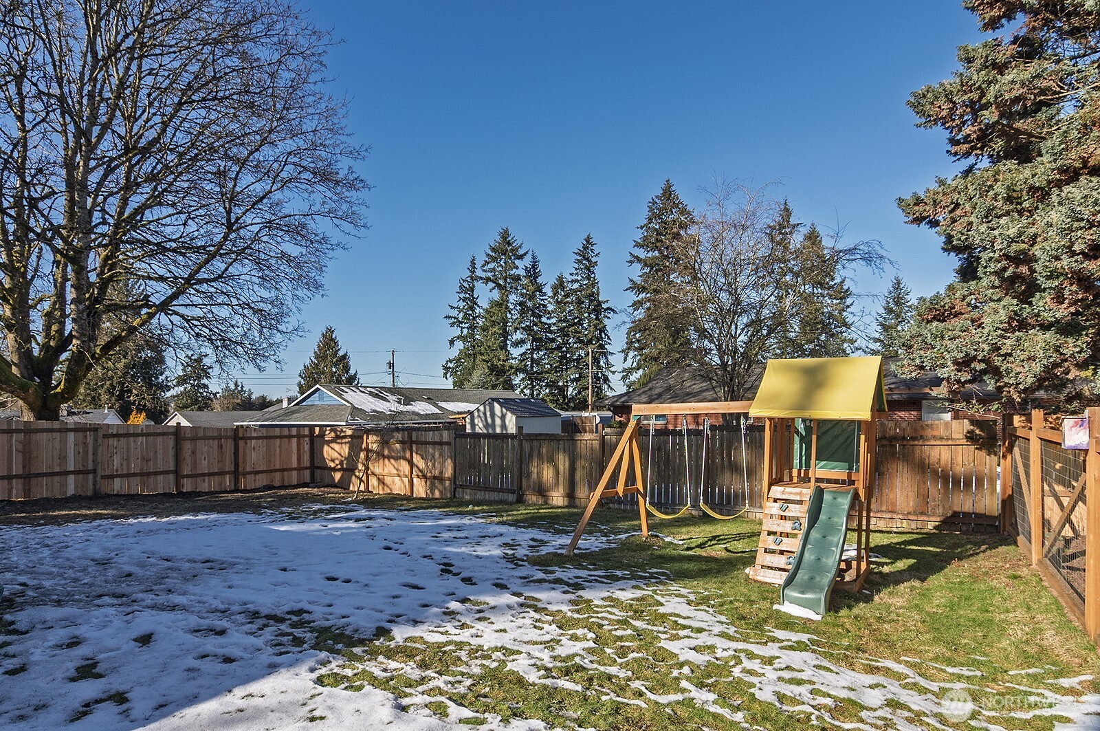 Massive, fully fenced yard with dog run, play structure, and gardening space.