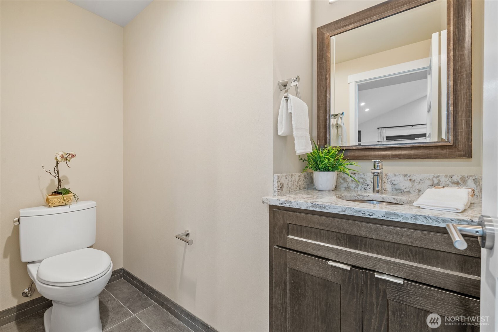 The elegant powder room features a sleek vanity with a quartz countertop, a premium Toto toilet, and a stylish Hansgrohe faucet.