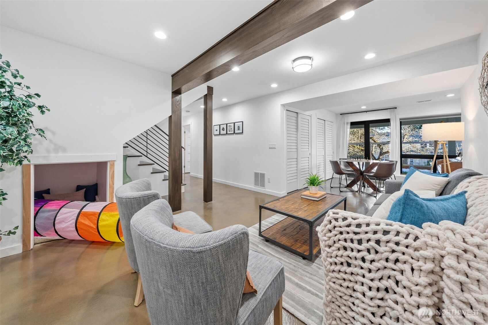 The family room features a great flow, seamlessly connecting to two additional bedrooms, a full bathroom, and the utility room. Notice the charming built-in kid's nook under the stairs adds a playful touch, creating a cozy hideaway for little ones.