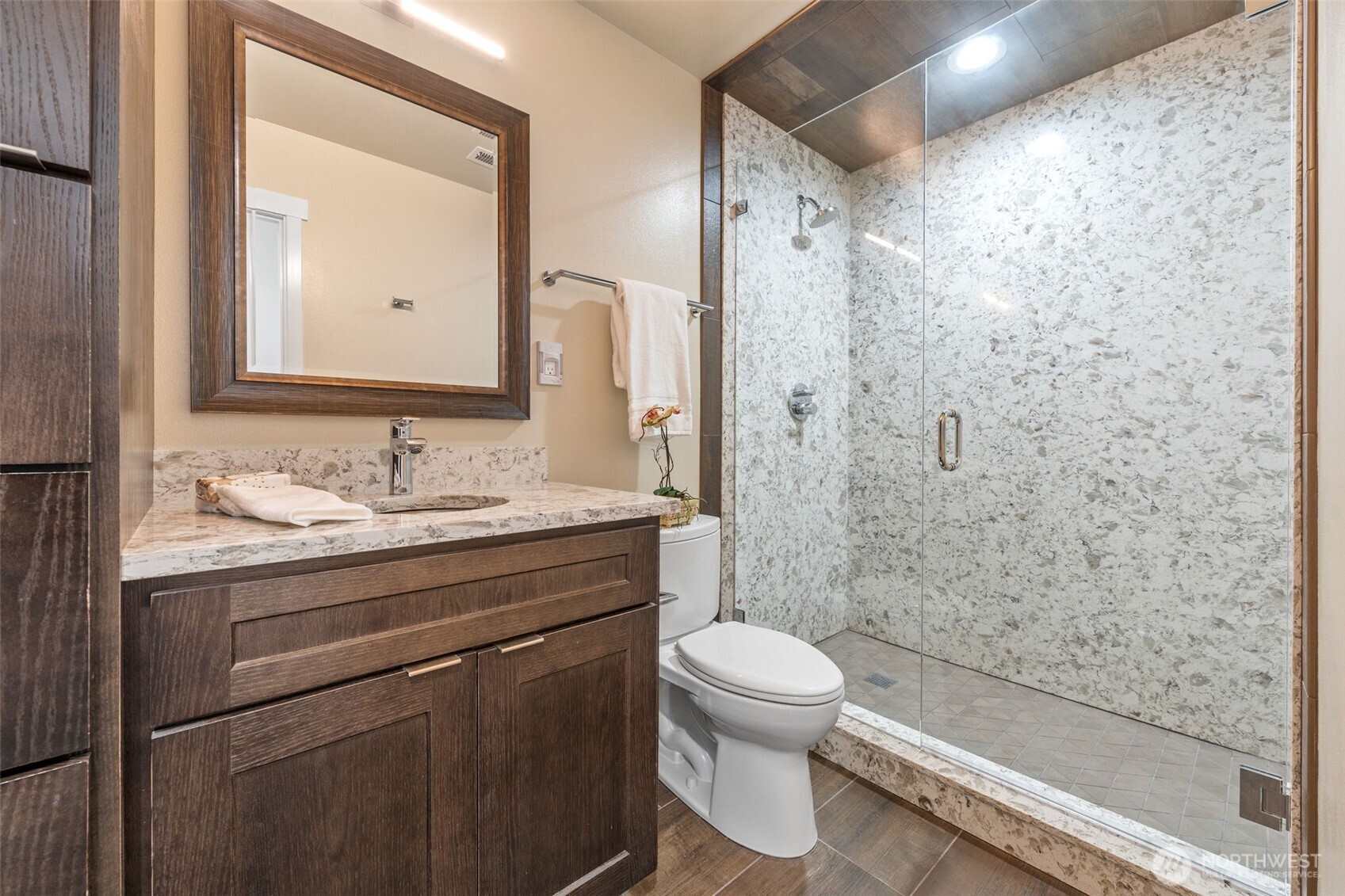 The lower-level bathroom features ample storage to keep everything organized and within reach. The spacious walk-in shower, adorned with elegant tile, adds a touch of luxury and convenience. Notice the updated Hansgrohe® faucet and Toto toilet—no expense was withheld during this remodel, ensuring top-quality design.