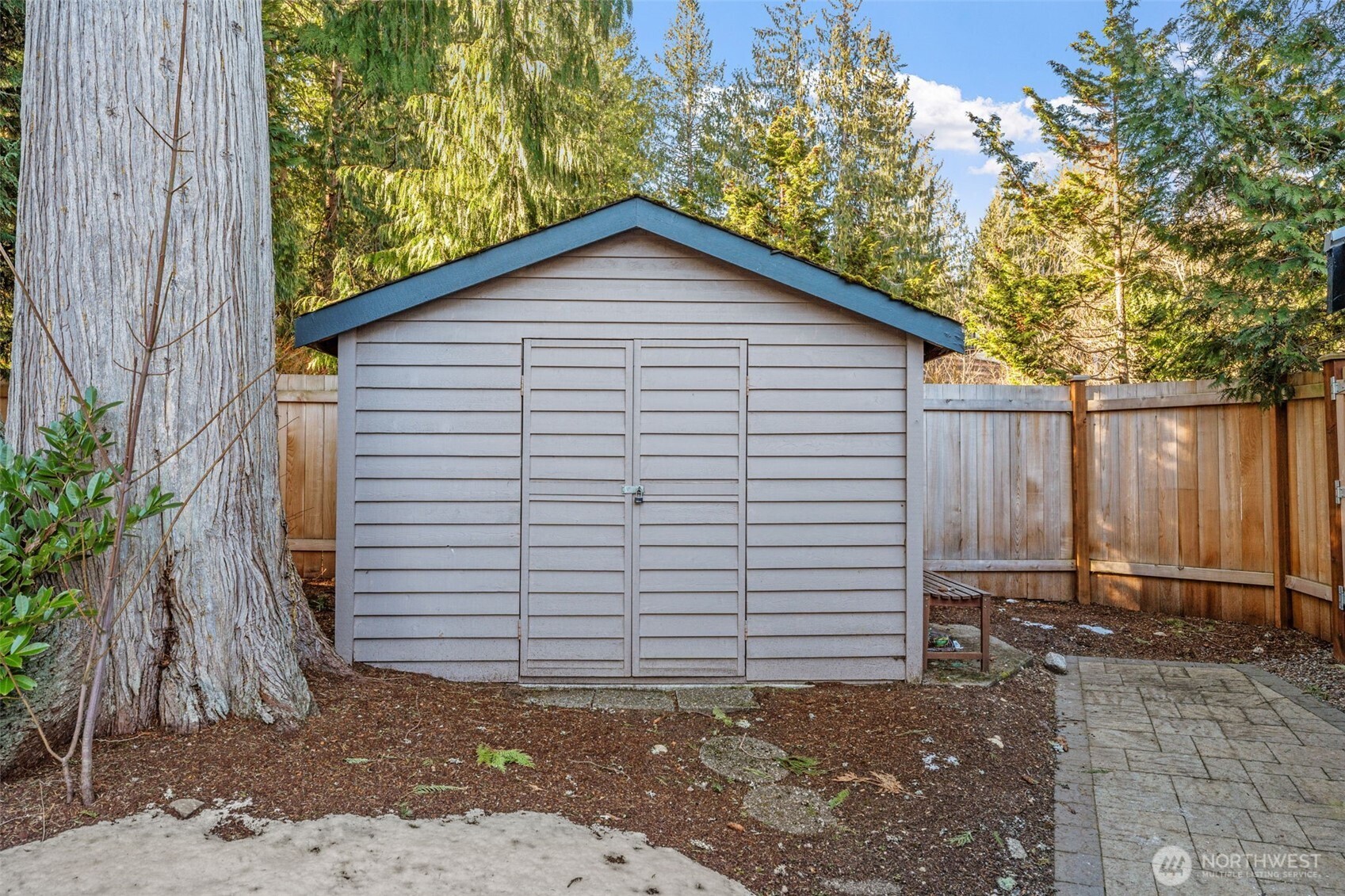 Nestled in a private corner of the yard, this versatile storage shed provides the perfect solution for keeping tools, outdoor gear, and seasonal items neatly organized.