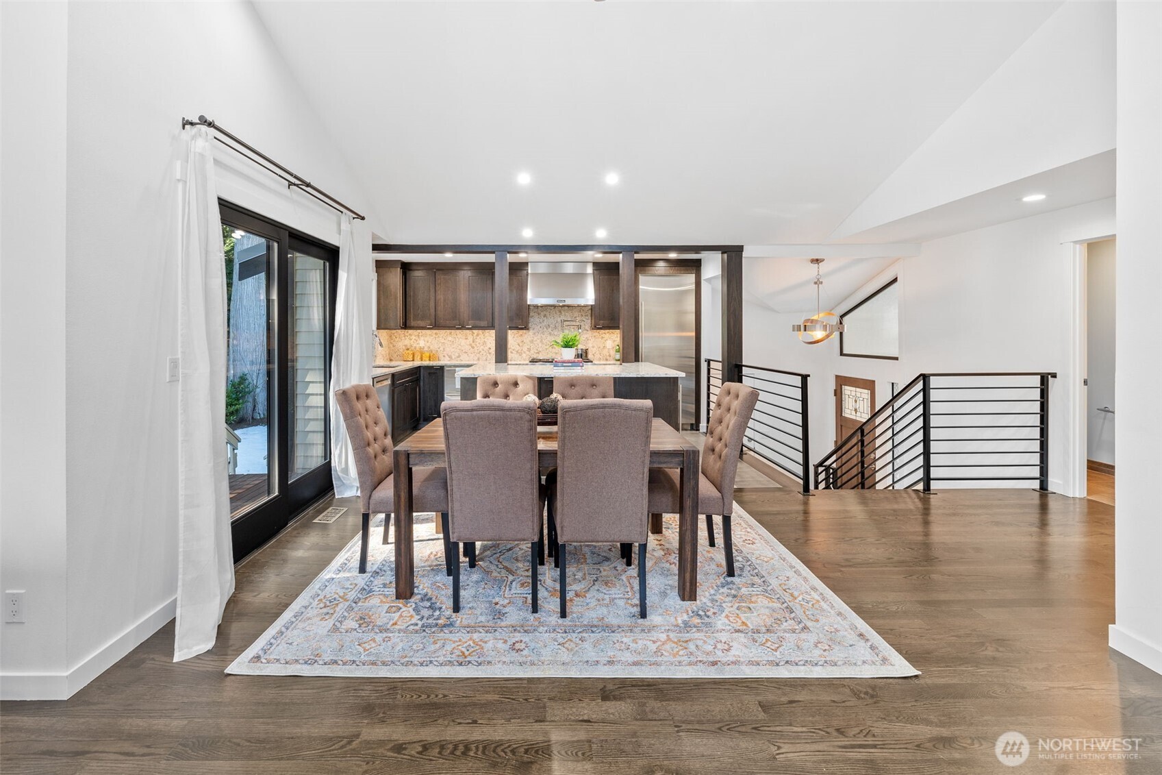 This stunning open-concept dining area seamlessly connects to a chef's kitchen, featuring rich cabinetry and sleek modern finishes.