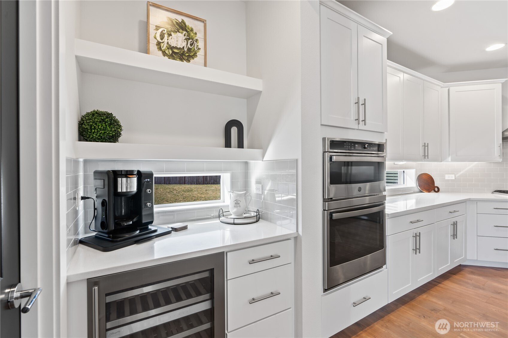 Opulent chef's kitchen featuring quartz counters, double oven, expansive fridge, ample storage, and wine beverage refrigerator.