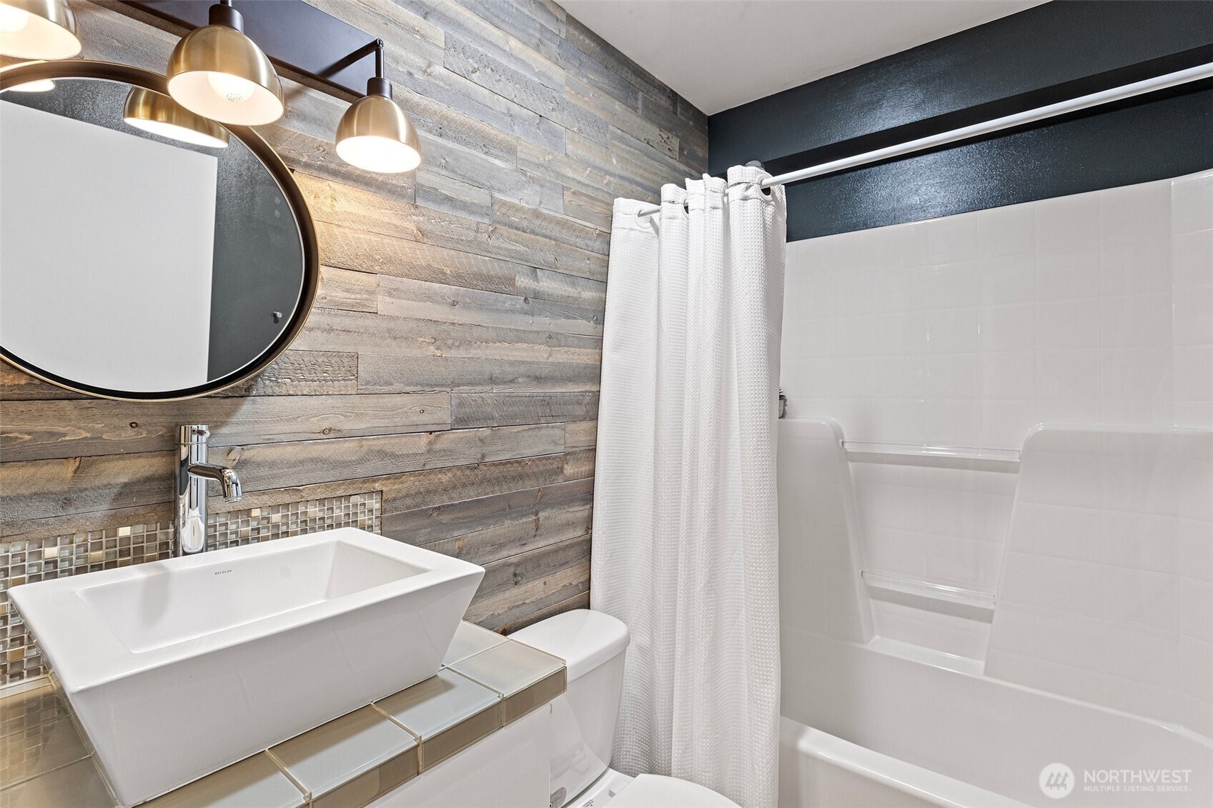 Entry level full bathroom with custom finishes, extra shelving, tub surround, large floor tiles and vanity with vessel sink and vessel faucet. Features a rain shower and hand-held shower combination.