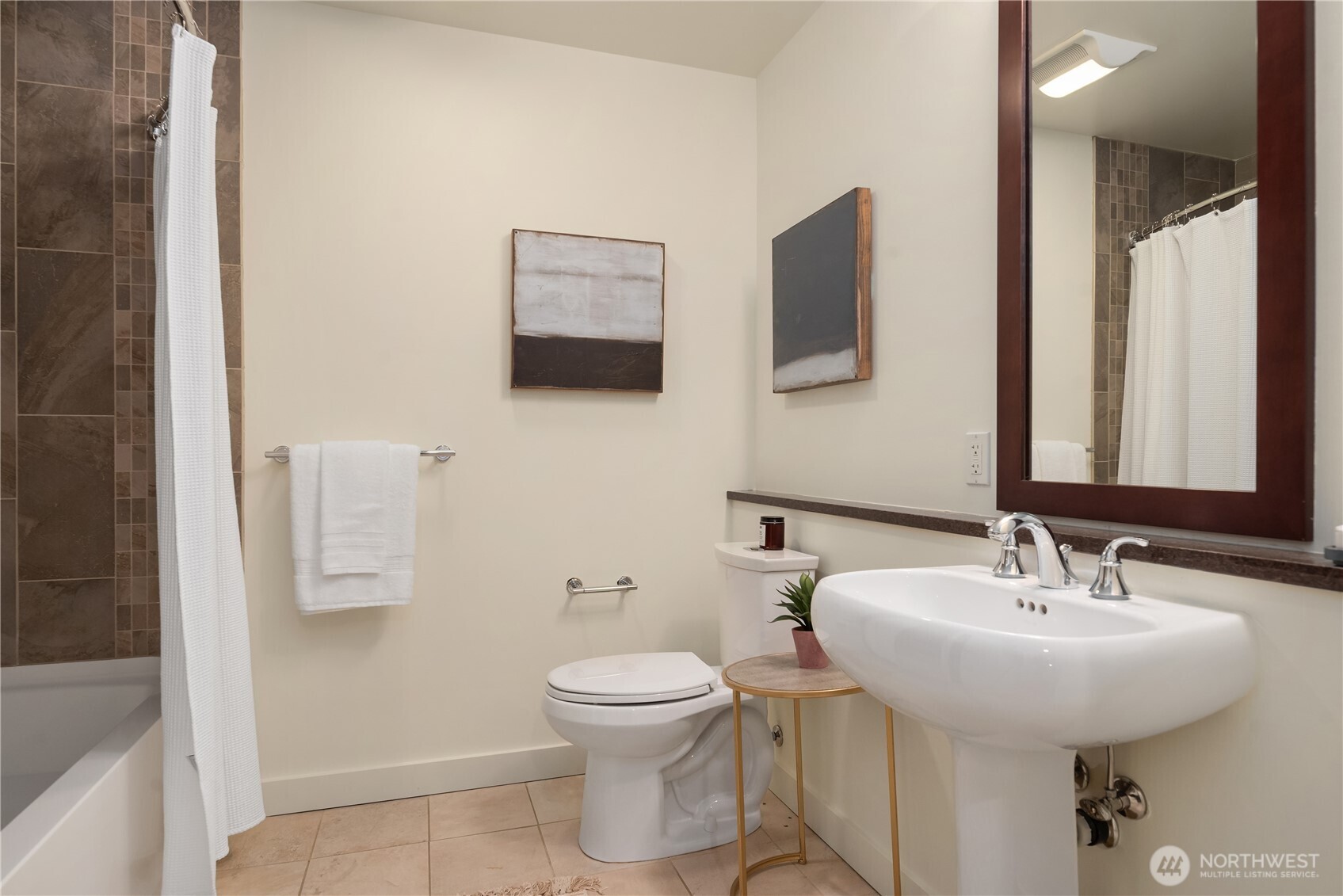 The main bath located off the second bedroom is oversized with designer tile work and a pedestal sink.