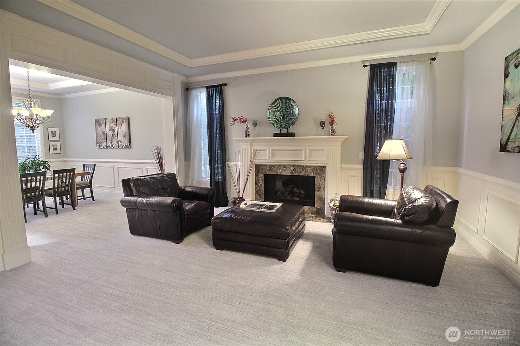 Formal Living room with gas fireplace, wood mantle and marble tiles surrounding it. Crown & Cove Molding and Wainscoting decorate this comfortable room.