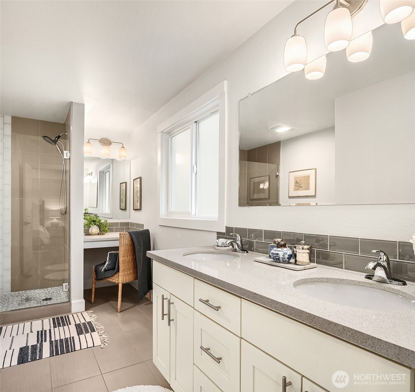 A spacious step-in shower with subway tile accent and shiny glass shower doors.