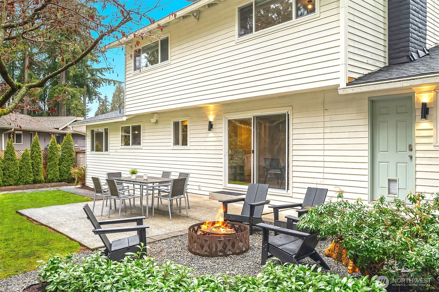 A side view of the home showcased by the classic horizontal wood slat fence with convenient access door. Only a few steps lead up to your private patio and fire pit.