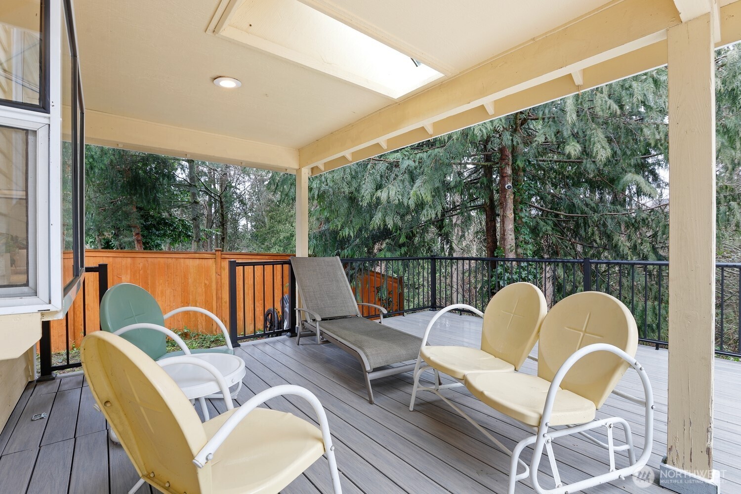 Spacious partially-covered deck with new composite decking over looking serene forest.