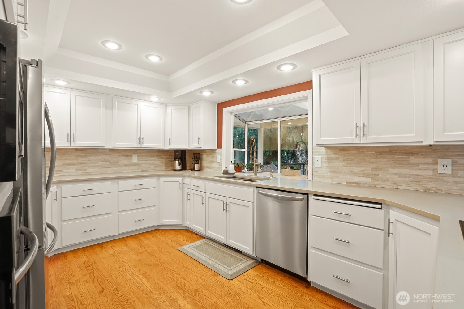 Newly updated kitchen with quartz counters, tile backsplash, and stainless appliances.