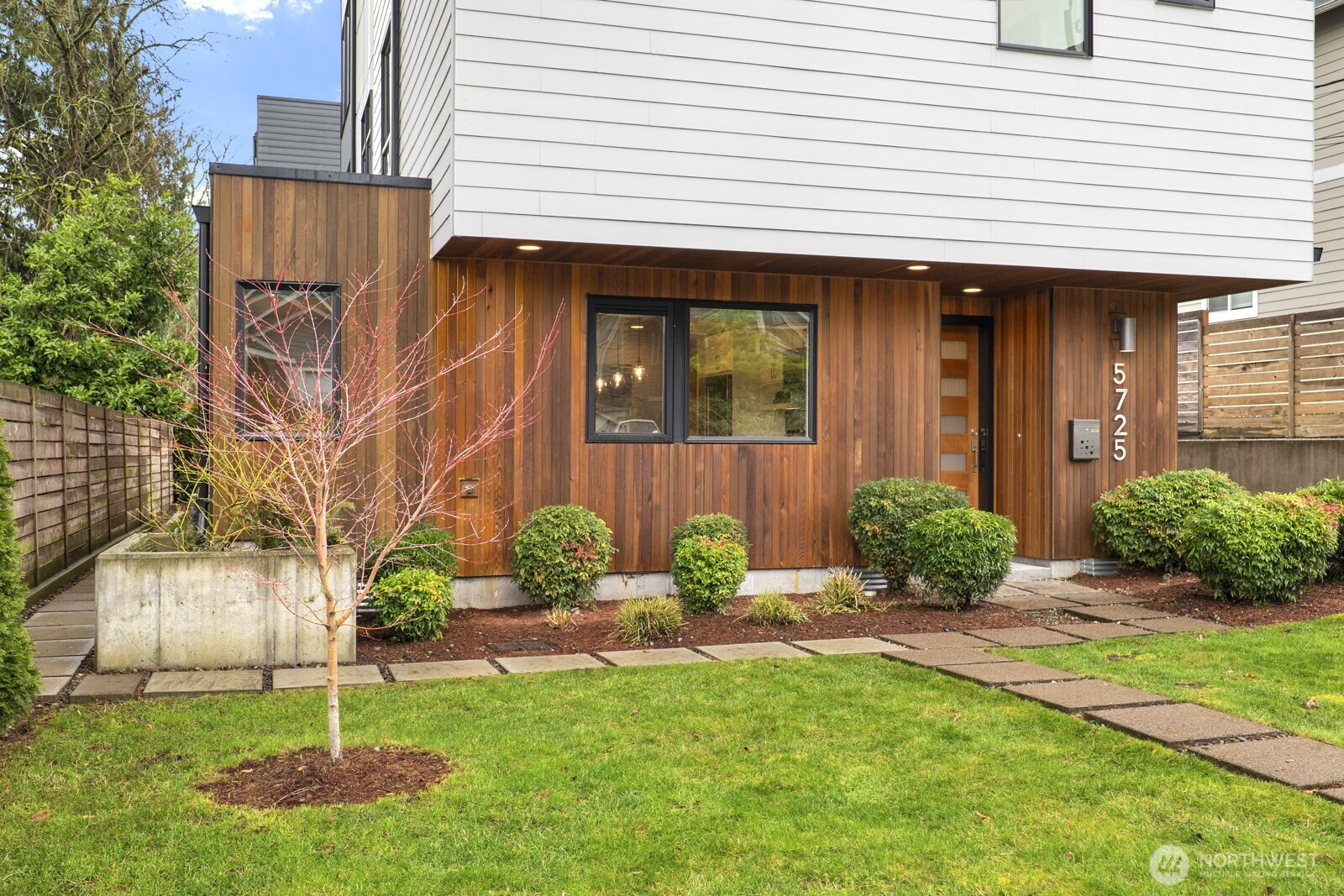 Exterior includes designer touches including vertical wood siding and mature landscaping.