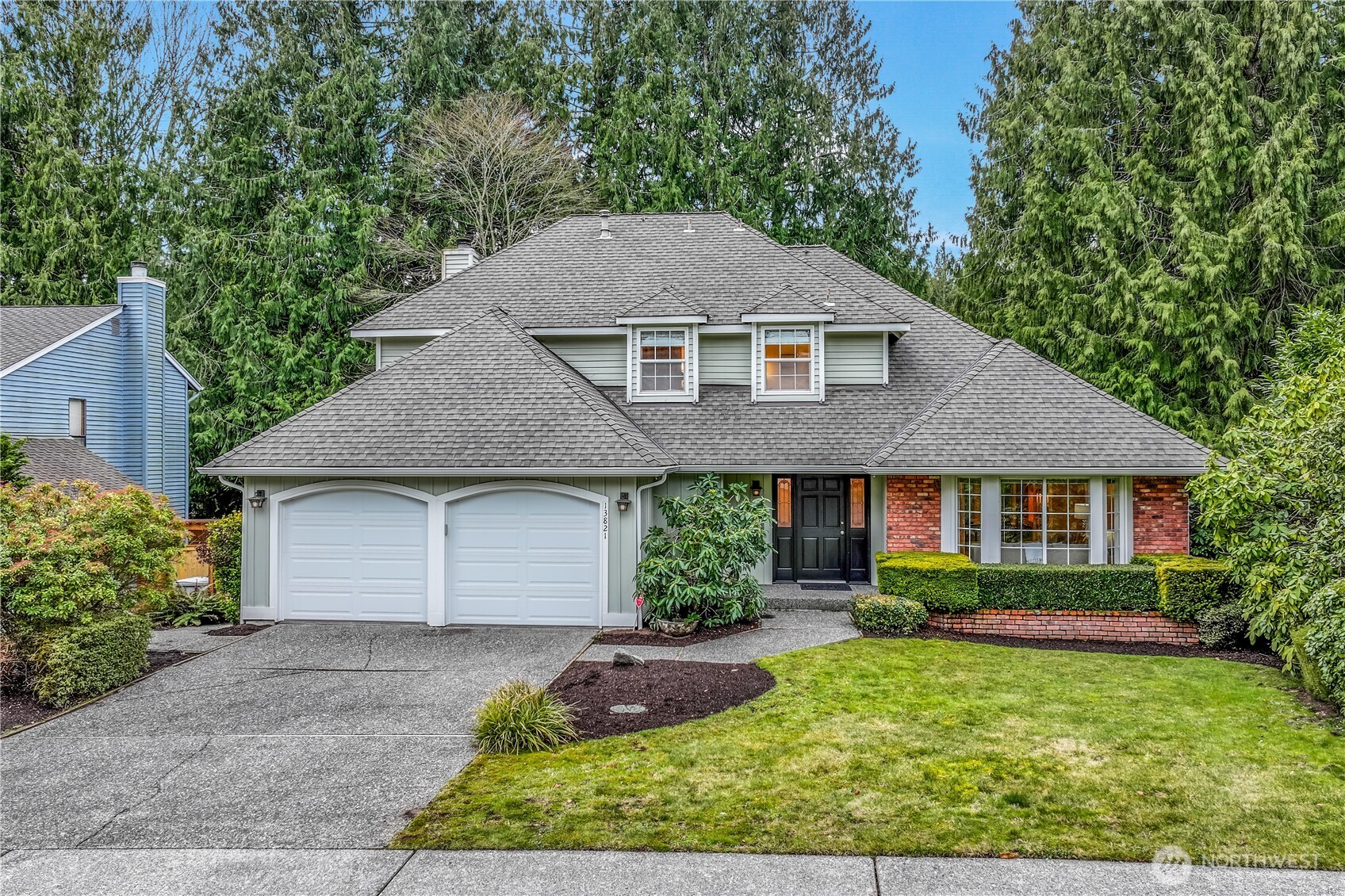 A bright and inviting façade set against lush greenery. The home's well-manicured front lawn and landscaped garden beds frame the property, creating a picturesque setting.