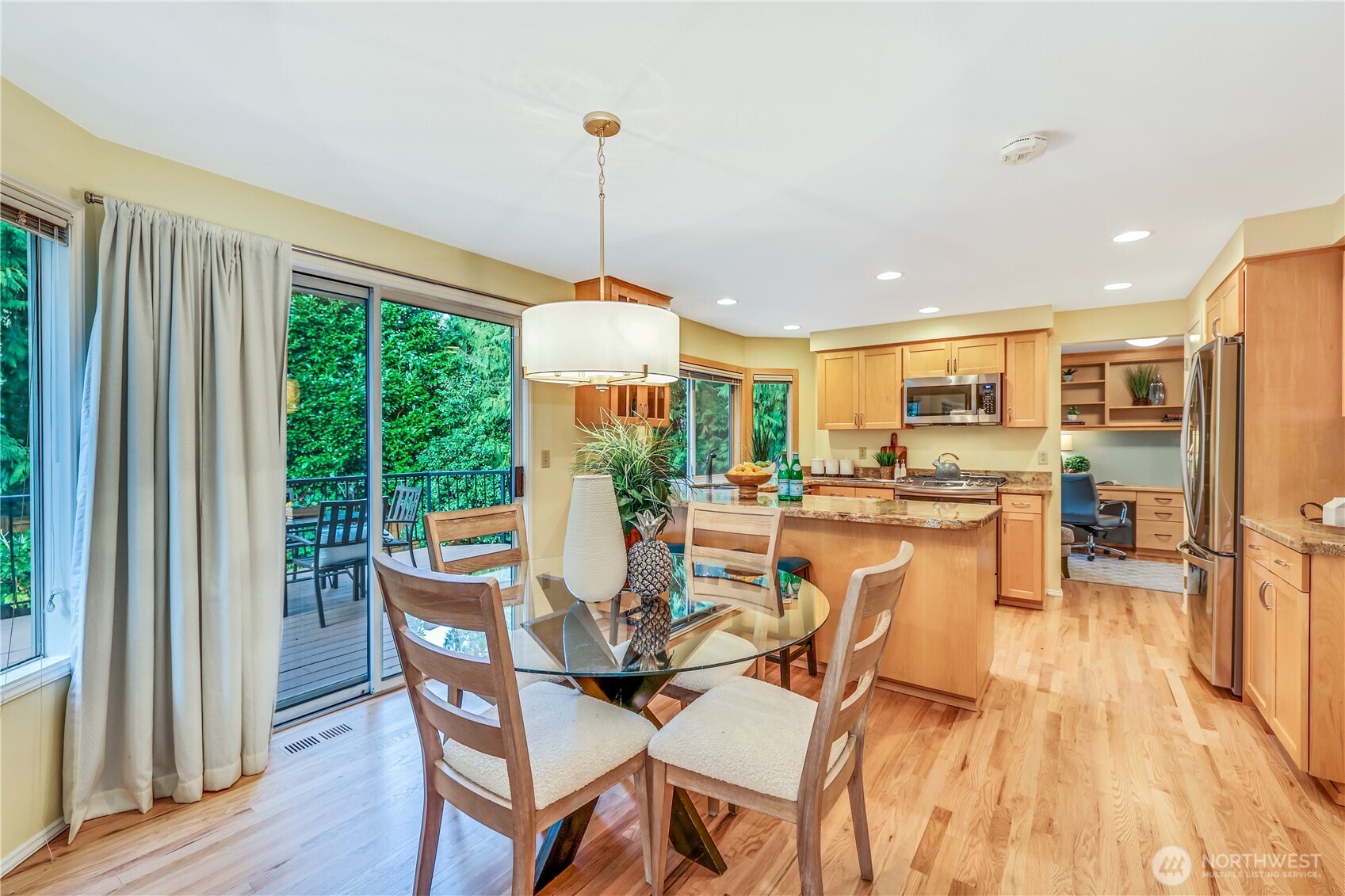 This open-concept kitchen and dining area offers abundant natural light, thanks to large windows and sliding glass doors that lead to the deck. The refinished hardwood floors add warmth, while the spacious layout allows for easy meal preparation and entertaining. Granite countertops provide durability and elegance, making this kitchen both stylish and functional.