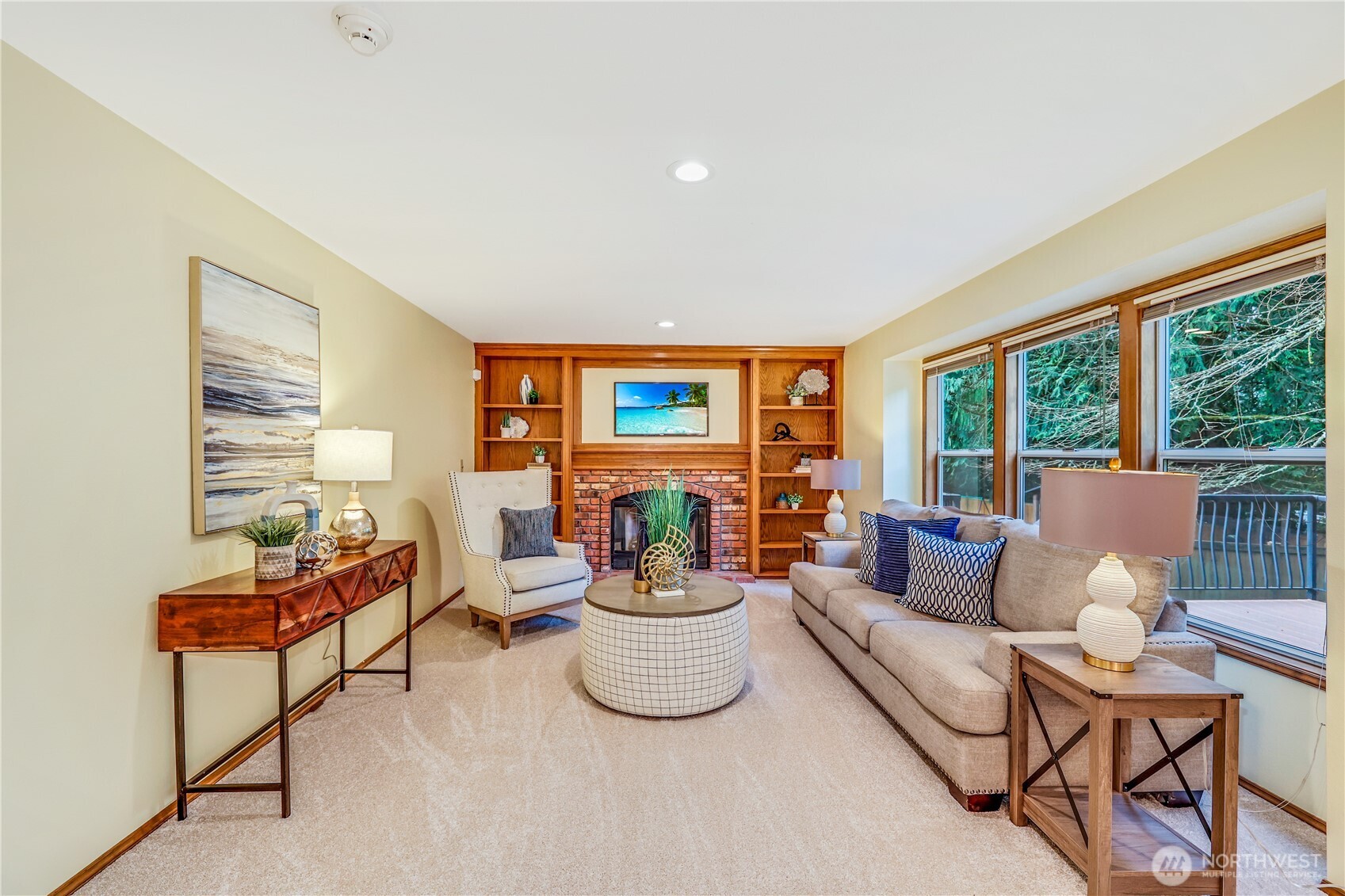 The inviting family room features a classic brick fireplace flanked by built-in wooden shelving, creating a warm and timeless ambiance. Expansive windows frame views of lush greenery, bringing the beauty of English Hill indoors. The new carpet adds comfort underfoot, making this an ideal space to relax and unwind.