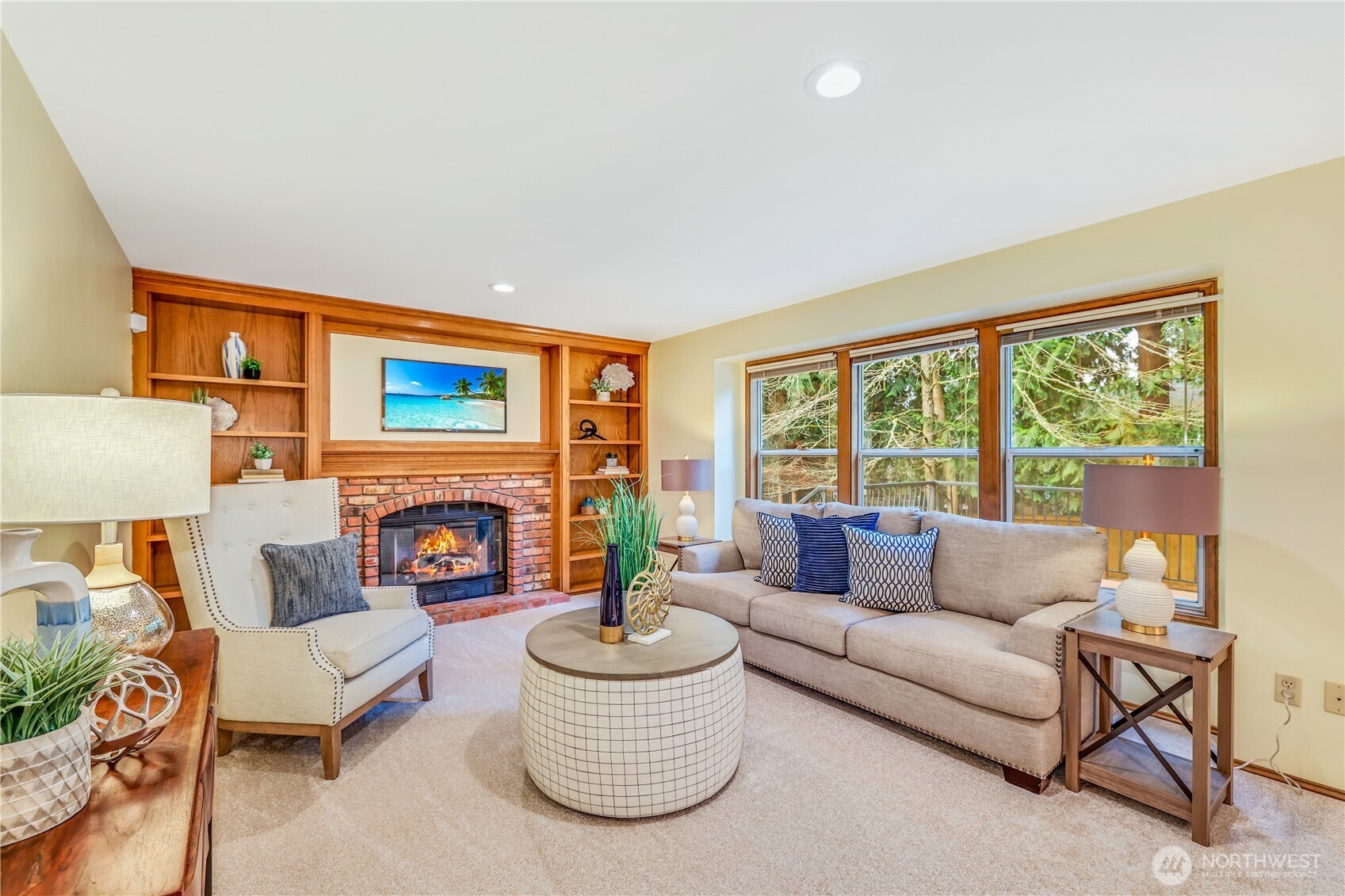 This angle showcases the large picture windows which allow for natural light to flood the space while providing a stunning view of the surrounding landscaped backyard.