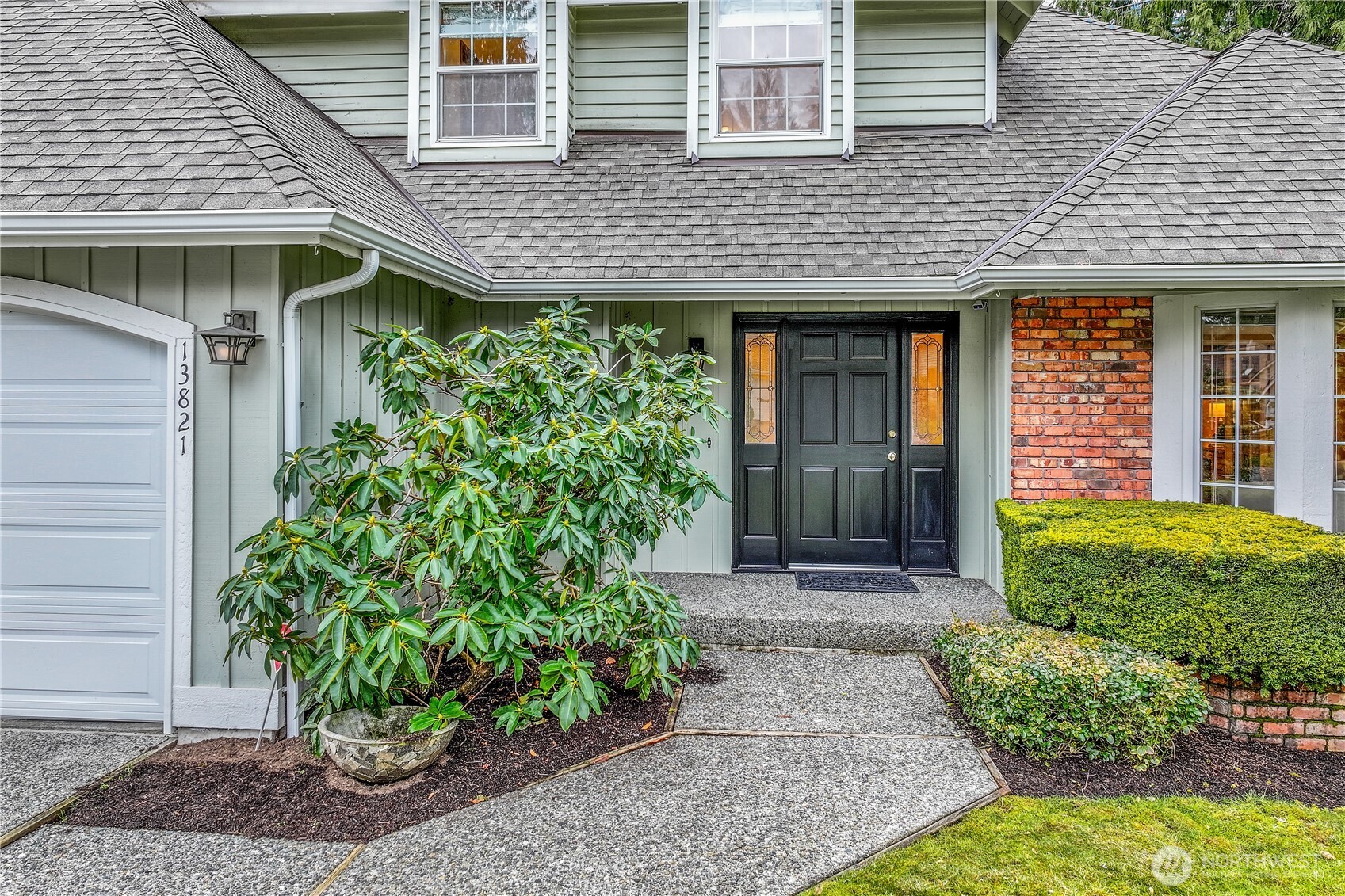 A closer look at the charming front entrance, featuring a classic black door with decorative glass panels. The covered entry provides protection from the elements while adding to the home’s timeless character.