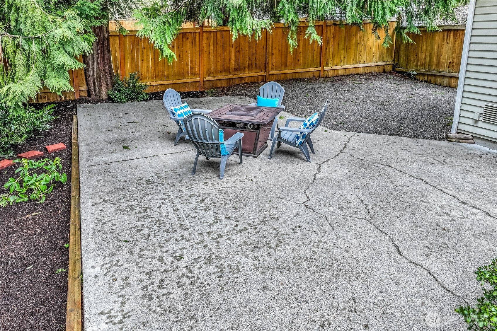 This lower-level patio provides a versatile outdoor space, ideal for setting up a fire pit or additional seating. The garden pathways and neatly arranged flower beds add character to this inviting backyard