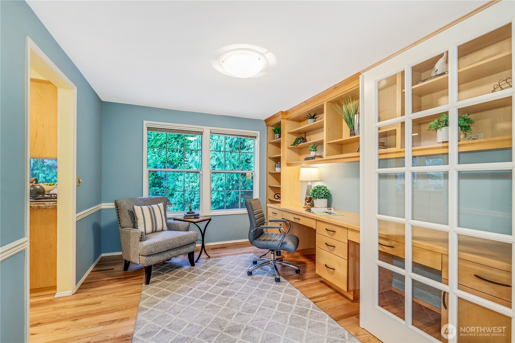 French doors lead into a dedicated home office space with built-in cabinetry and large windows overlooking the private yard. Ideal for remote work, this room offers a peaceful and productive environment. This room can also be converted back to a formal dining room.