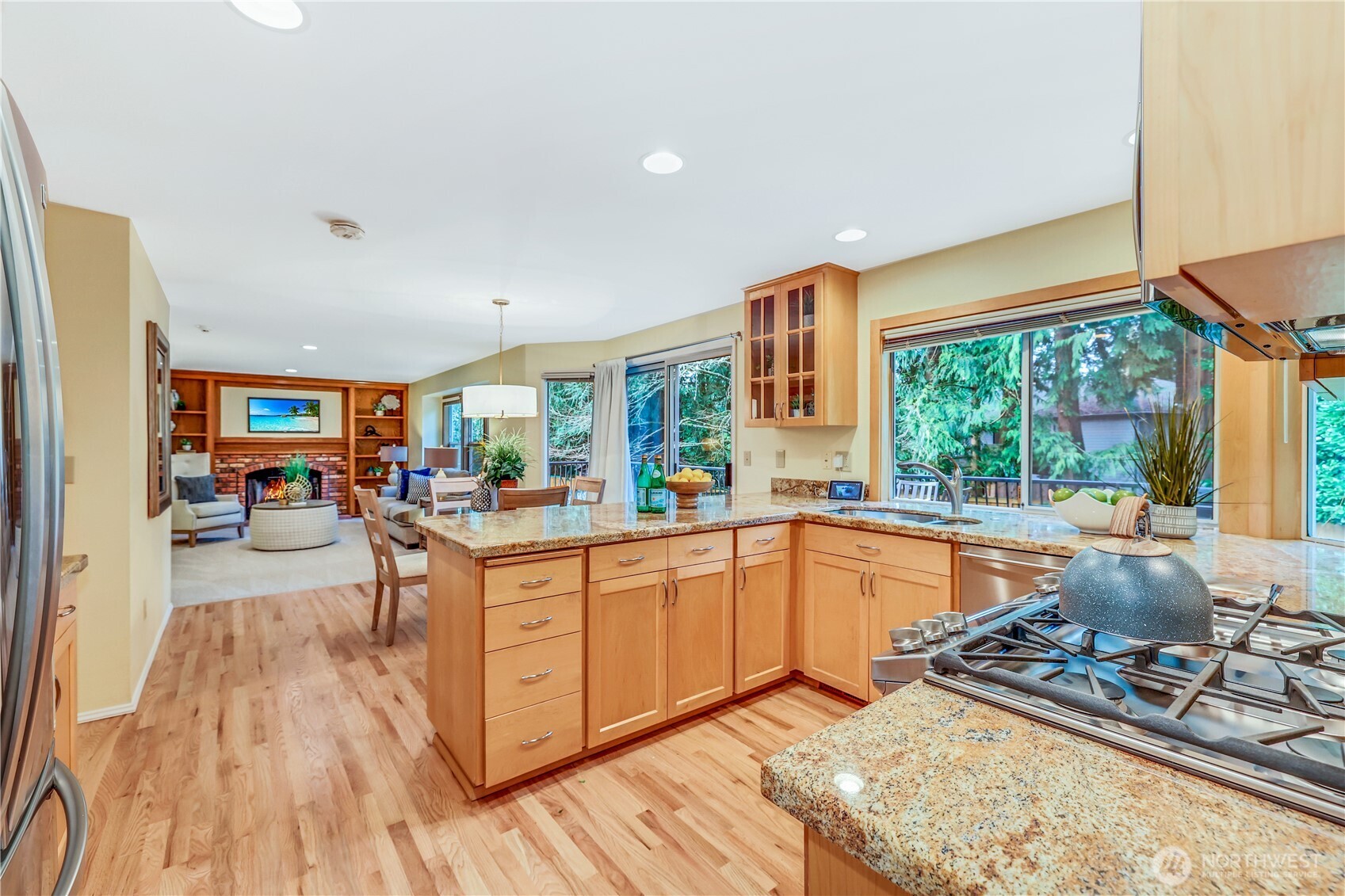 This chef’s kitchen features rich wood cabinetry, polished granite countertops, and a large breakfast bar. Stainless steel appliances, gas range, and an expansive window overlooking the backyard complete the space.