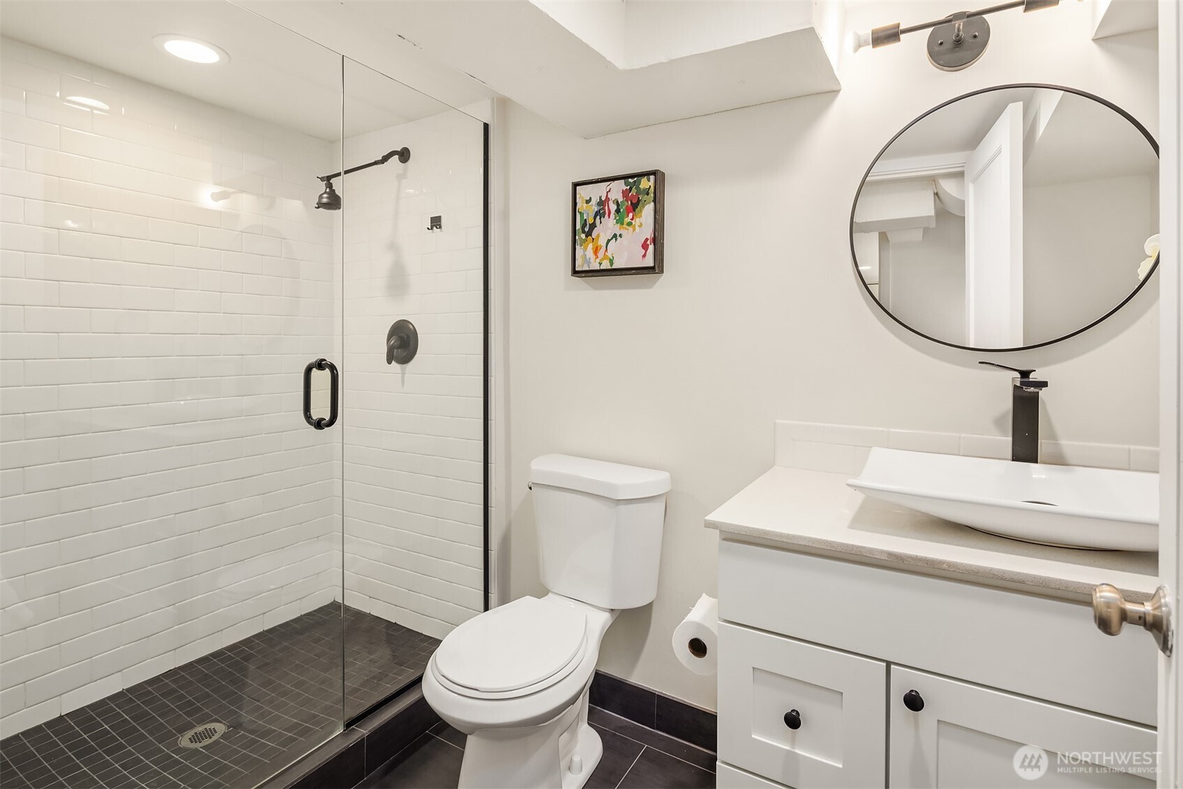 Lower-level renovated bathroom with big walk-in shower modern black and white embellishments.