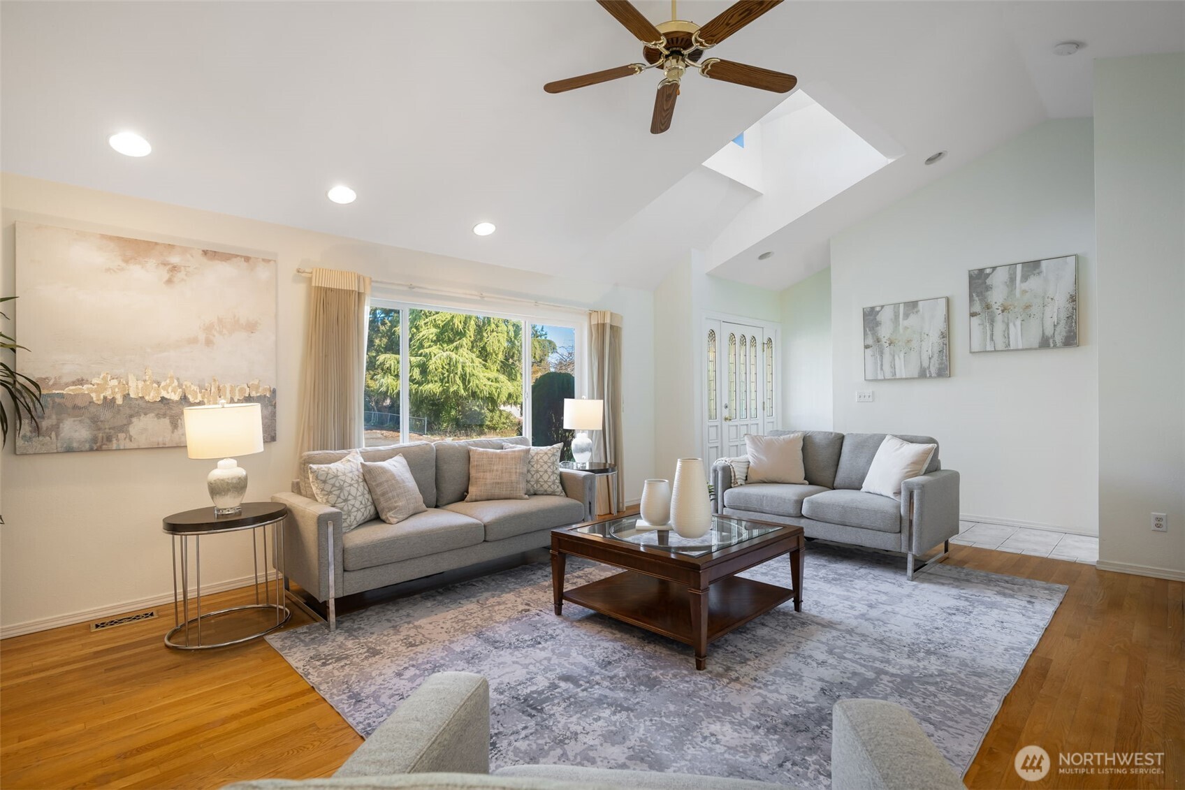 A living room with vaulted ceilings, oversized windows, gas fireplace, and original hardwoods.