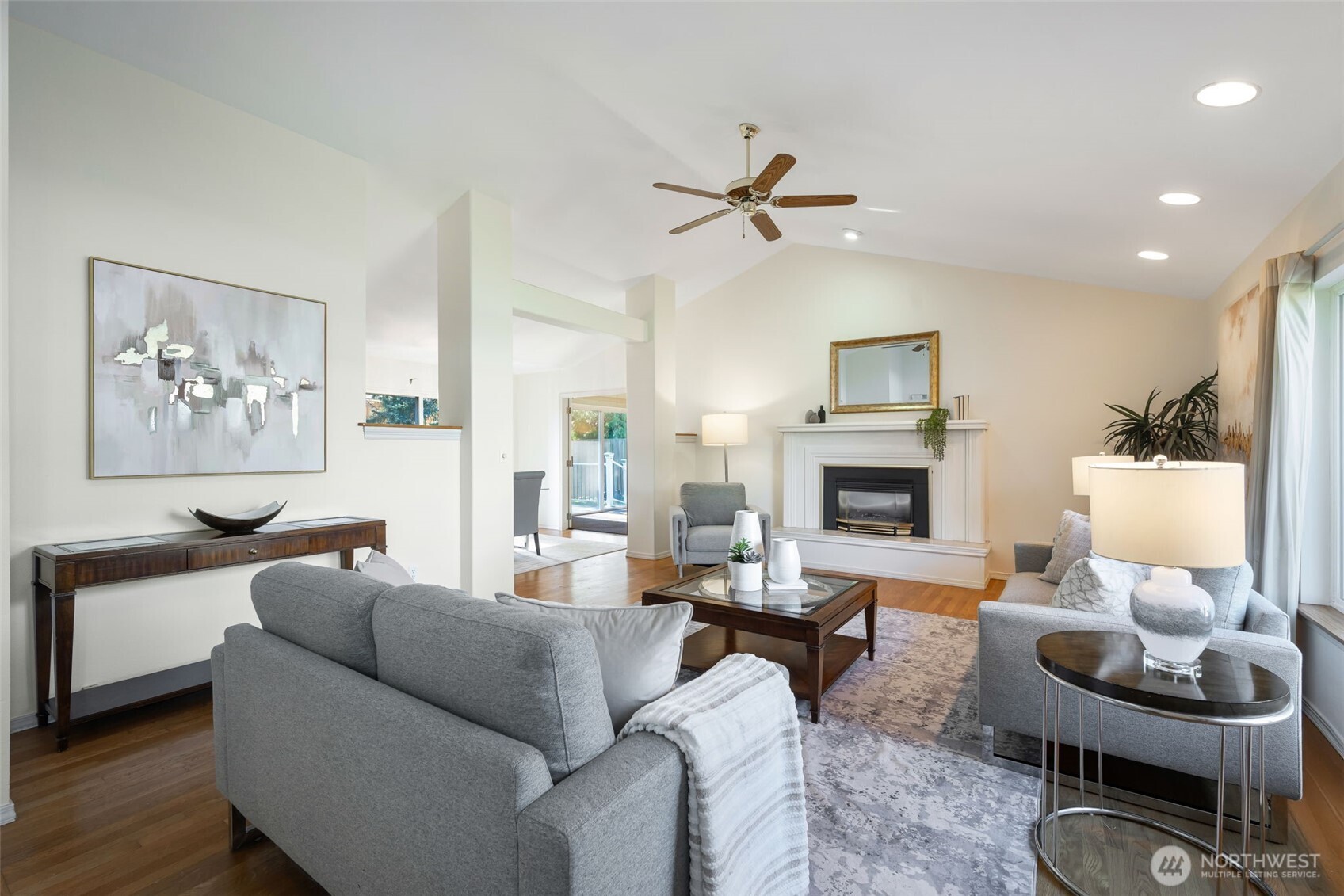 A living room with vaulted ceilings, oversized windows, gas fireplace, and original hardwoods.