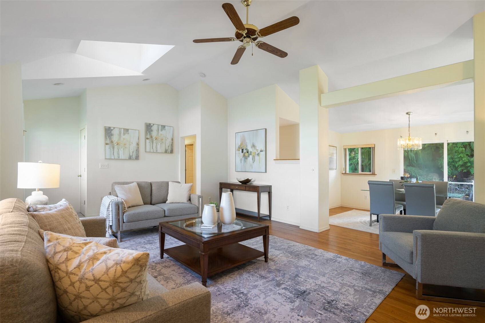 A living room with vaulted ceilings, oversized windows, gas fireplace, and original hardwoods.