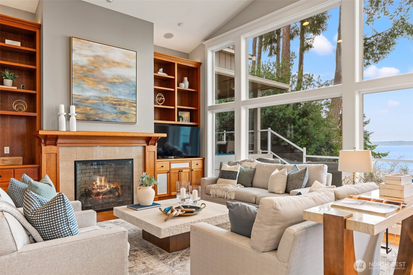 Open living room with fireplace, custom built-ins and a wall of windows to allow the natural light and to take in the stunning views.