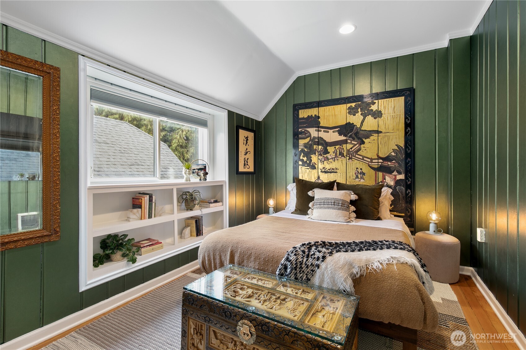 This inviting bedroom features rich green paneling and built-in shelving to create a distinctive retreat that feels both intimate and refined.