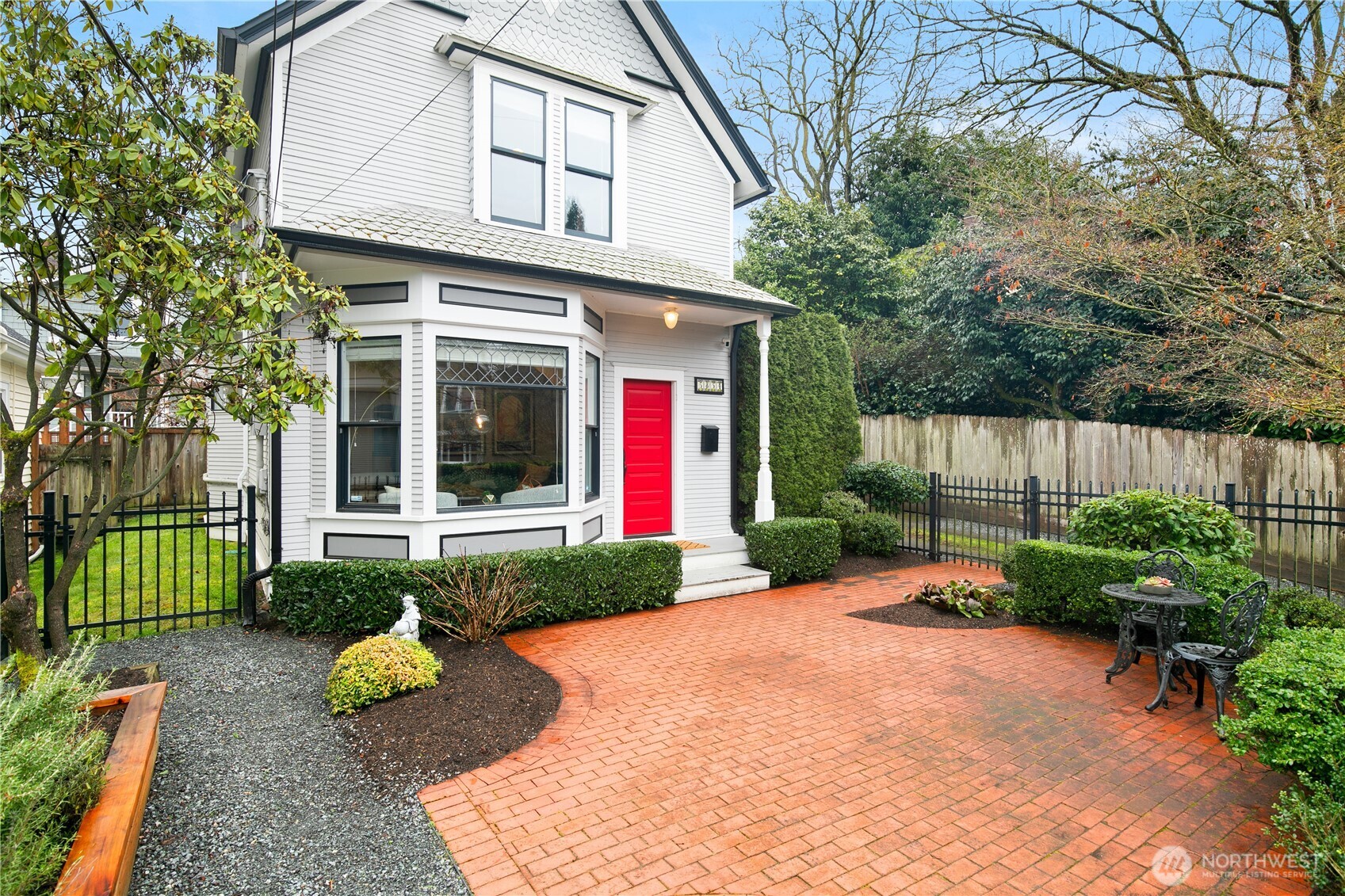 A show-stopping red door sets the tone for this charming, near–Green Lake residence. The brick-paved entry courtyard, manicured hedges, and elegant fencing create a striking first impression—truly capturing the pride of ownership.