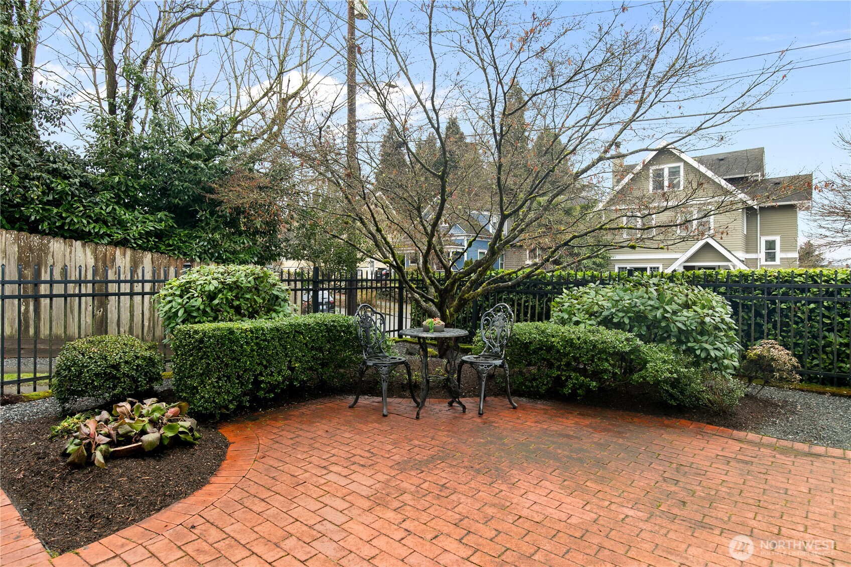 Welcome guests to a cozy outdoor conversation nook surrounded by immaculate topiary and classic brickwork. The serene courtyard adds a touch of elegance and curb appeal, illustrating the property’s commitment to both style and function.