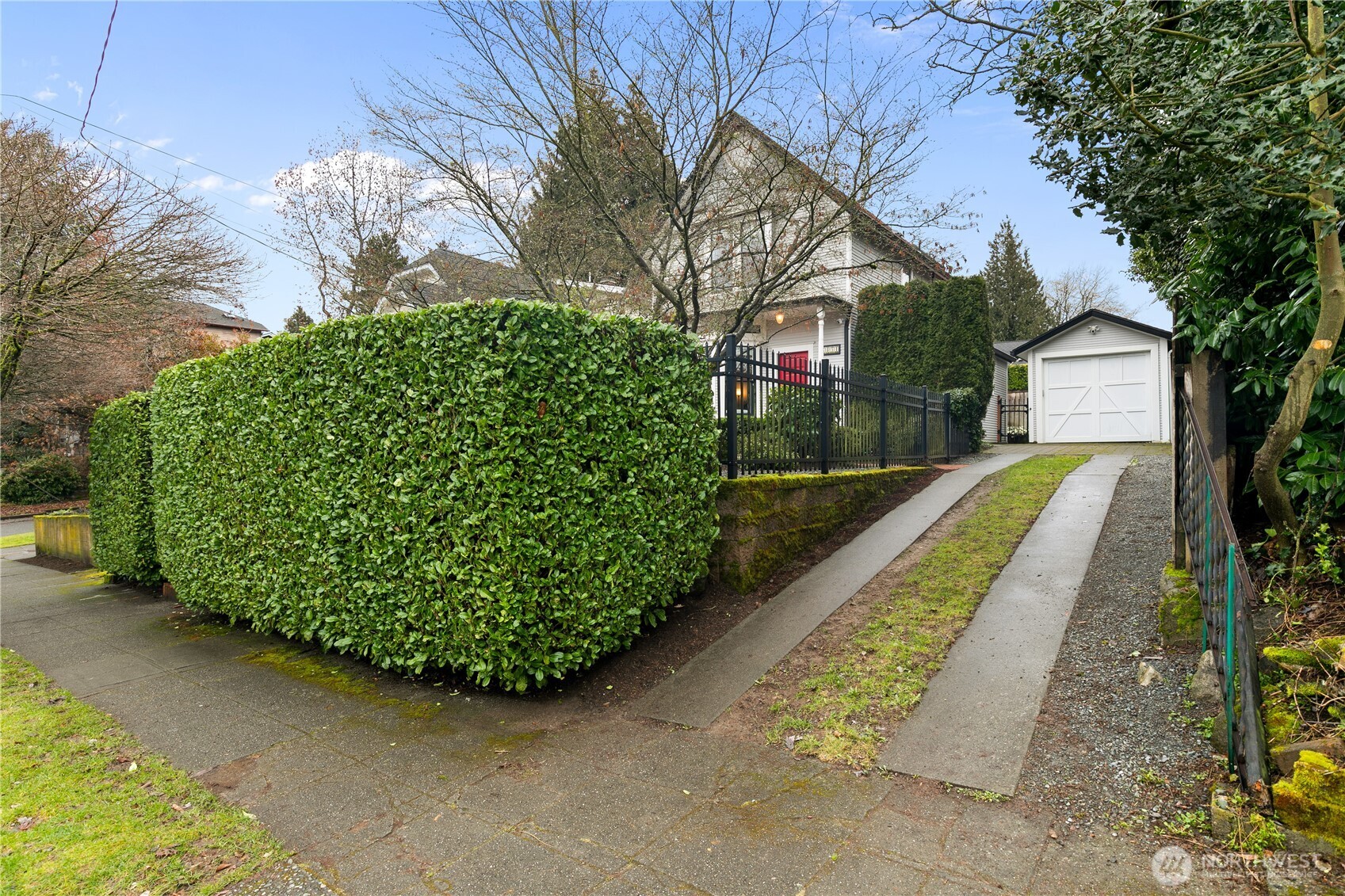 A meticulously trimmed hedge lines the driveway leading to a convenient detached garage—offering off-street parking and additional storage.